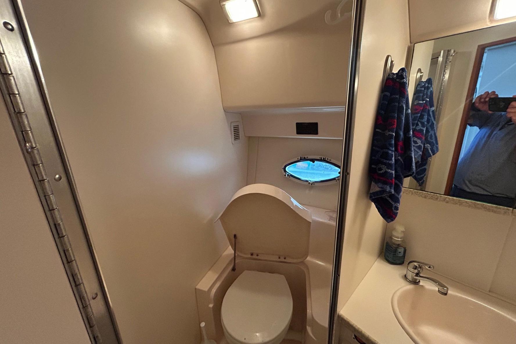 Bathroom interior of 2000 Silverton 352 Motor Yacht with sink and porthole window.