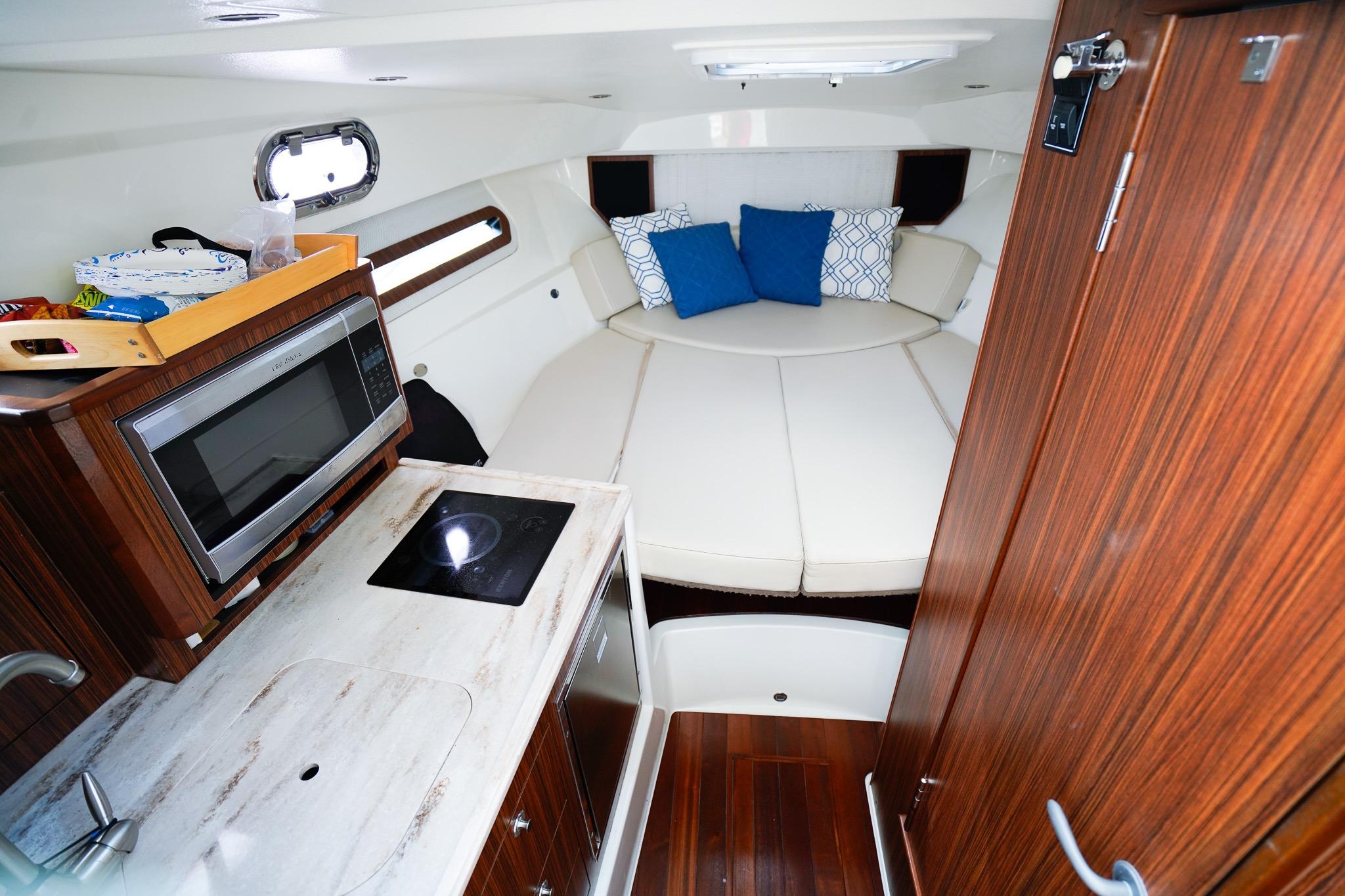 2020 Pursuit OS 325 Offshore cabin interior with kitchenette and cozy seating area.