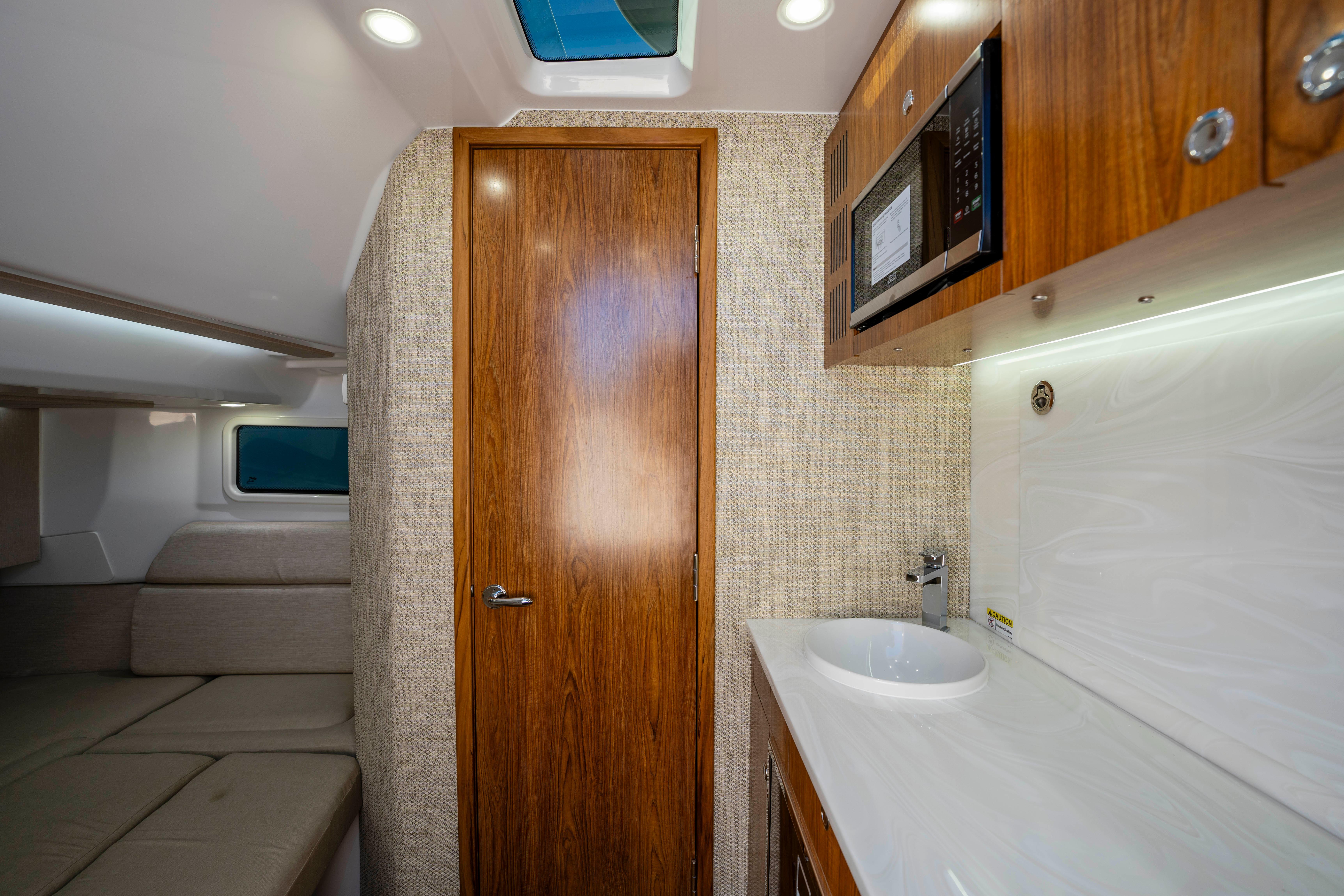 Interior of Everglades 455 Center Console 2026 with wood doors and sink.