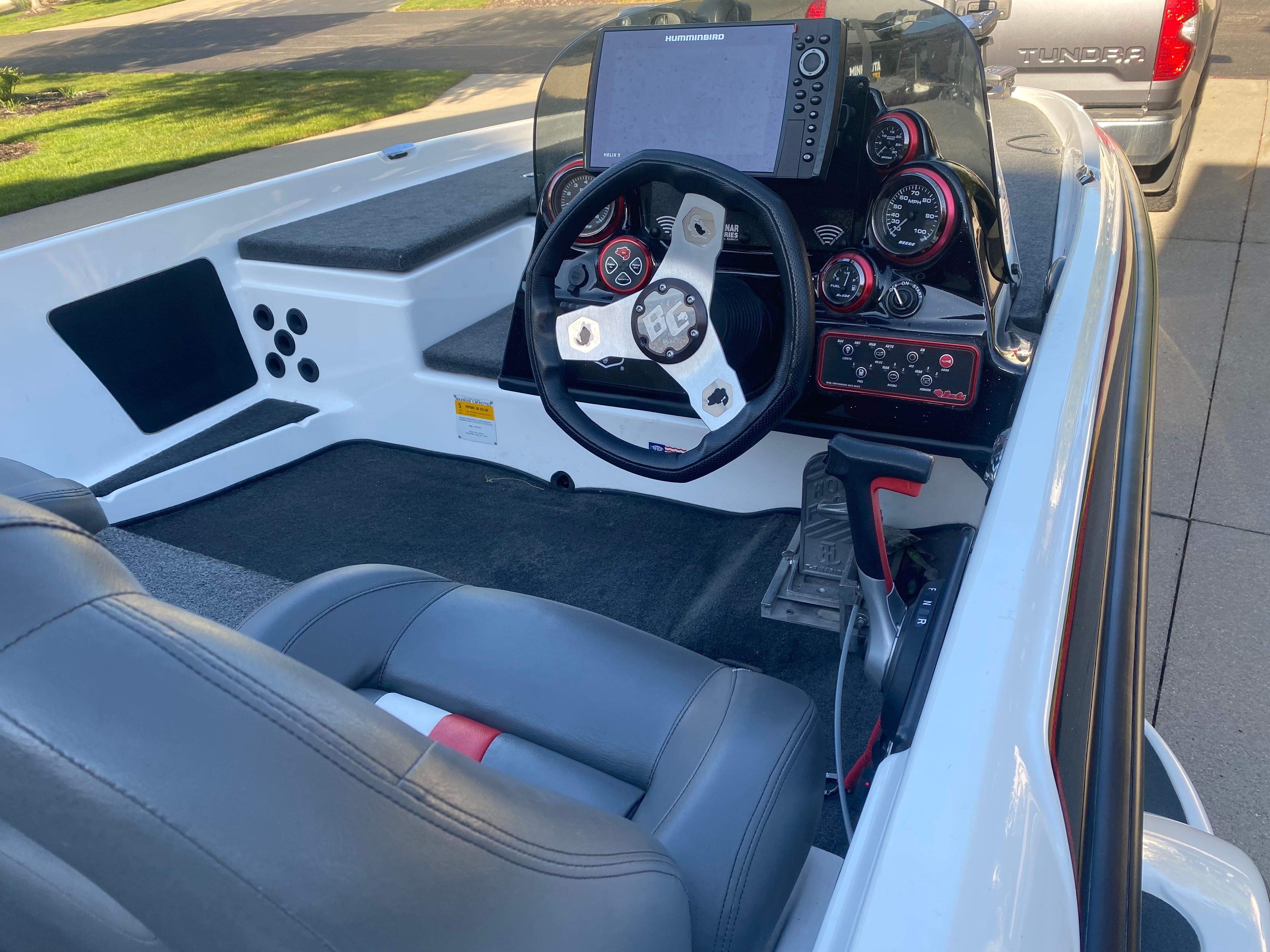 The image shows the cockpit of a 2014 Bass Cat Pantera II boat with gray seats and a steering wheel.