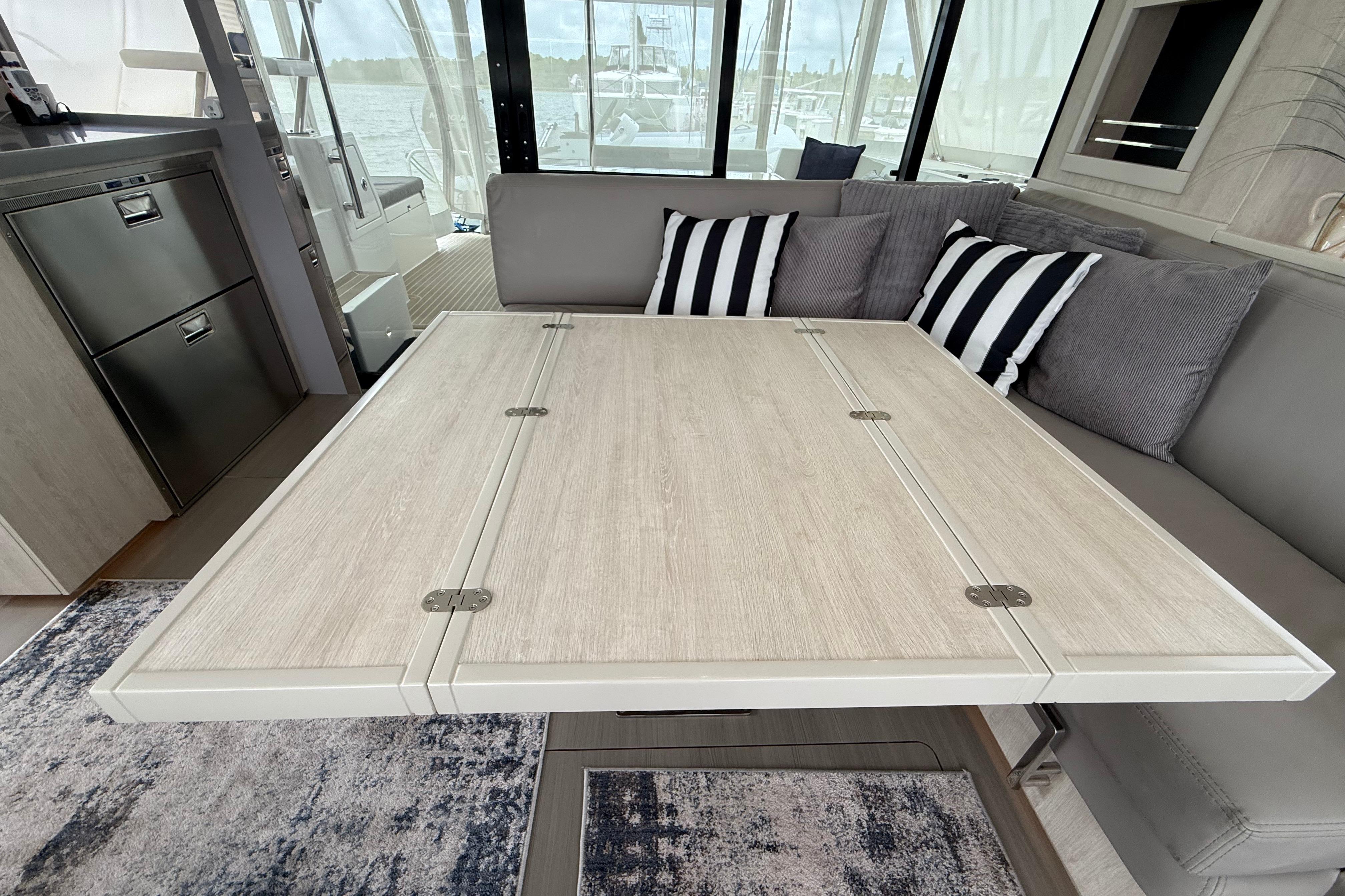Interior of 2021 Leopard 43 Powercat with foldable dining table and striped cushions.