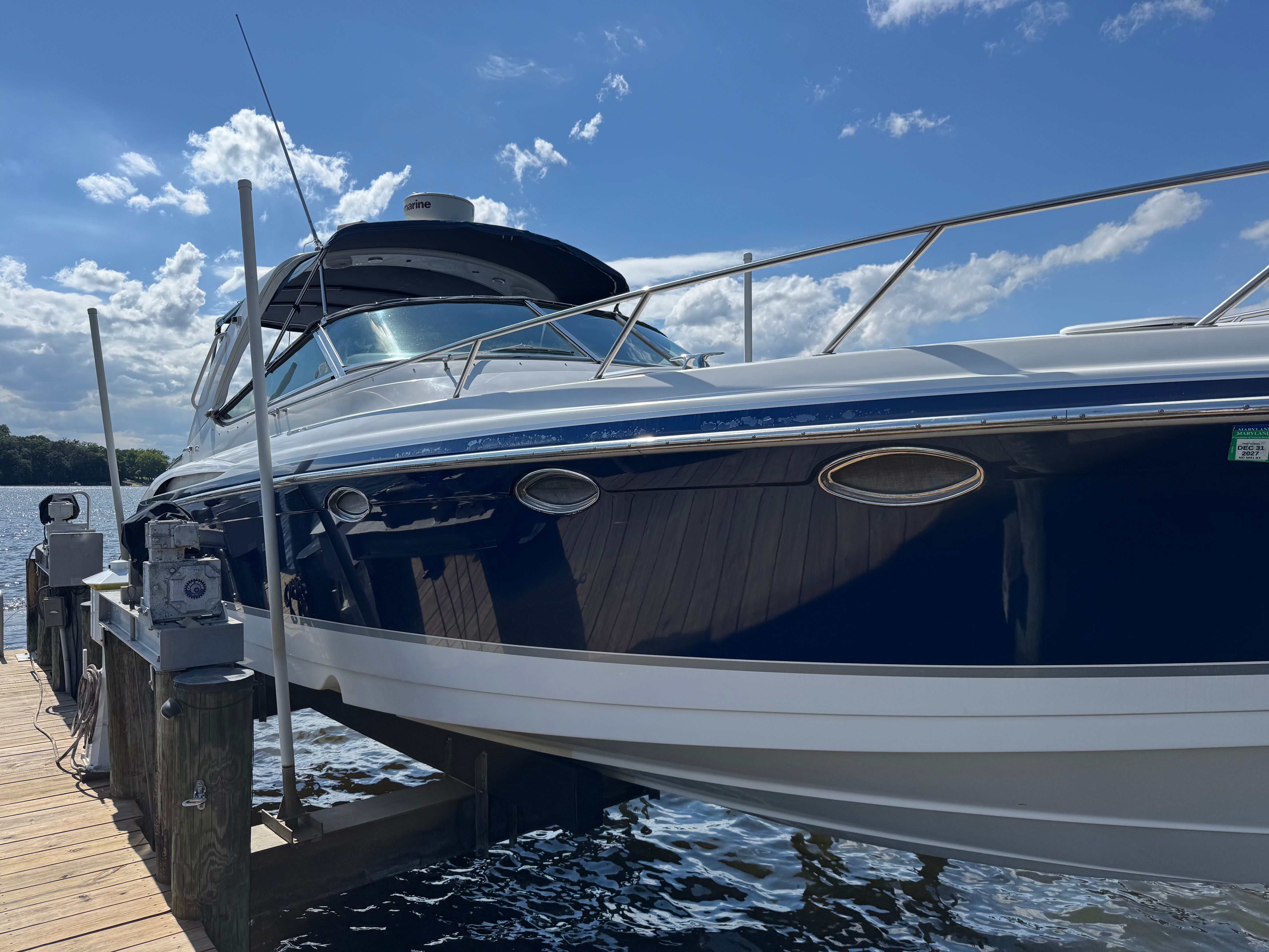 A sleek motorboat docked at a wooden pier, surrounded by water and blue sky.