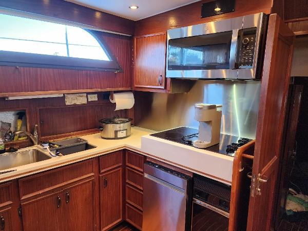 The 1980 Hatteras 53 Yacht Fisherman kitchen features wooden cabinets, a sink, and modern appliances.