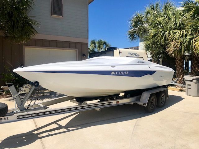 A white 2003 Baja 20 Outlaw boat on a trailer in a driveway.