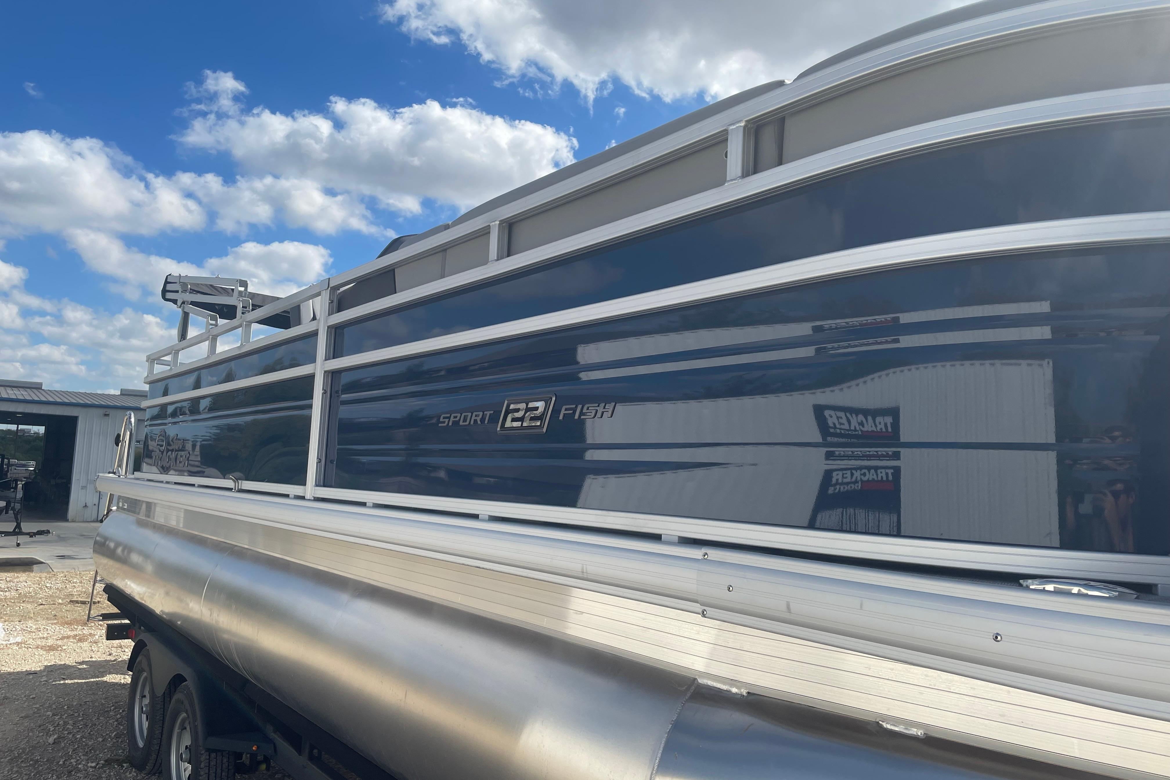 2026 Sun Tracker SportFish 22 DLX pontoon boat under a blue sky.