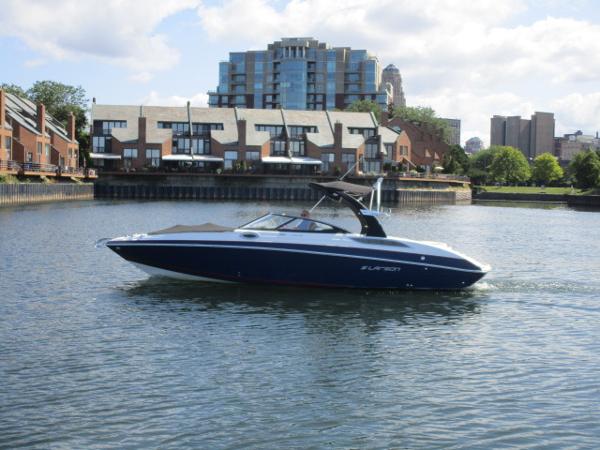 2017 Larson 292 LXI boat cruising on a calm urban waterway.