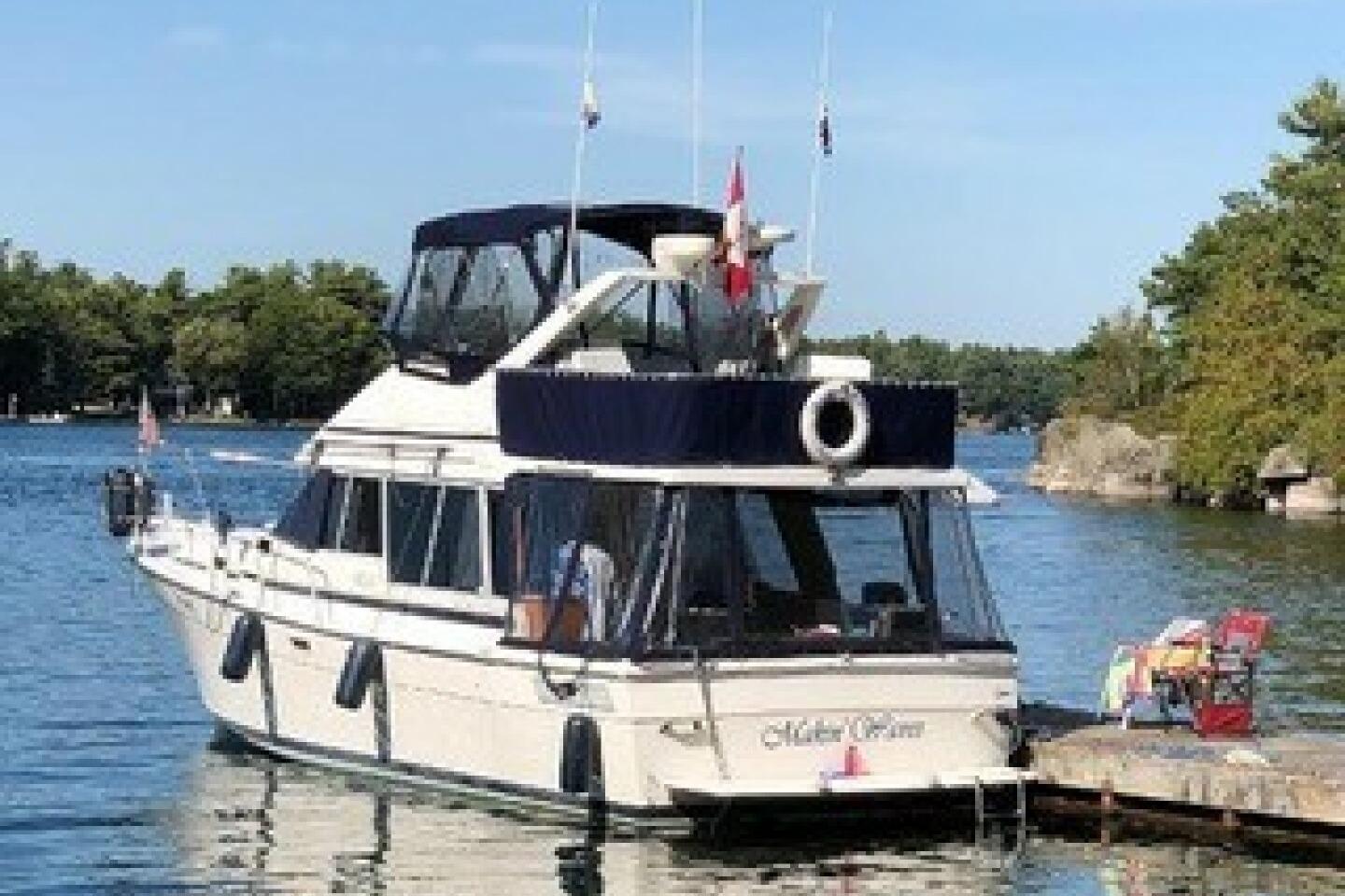 1986 Bayliner 3270 Motoryacht docked on a serene lake with lush greenery.