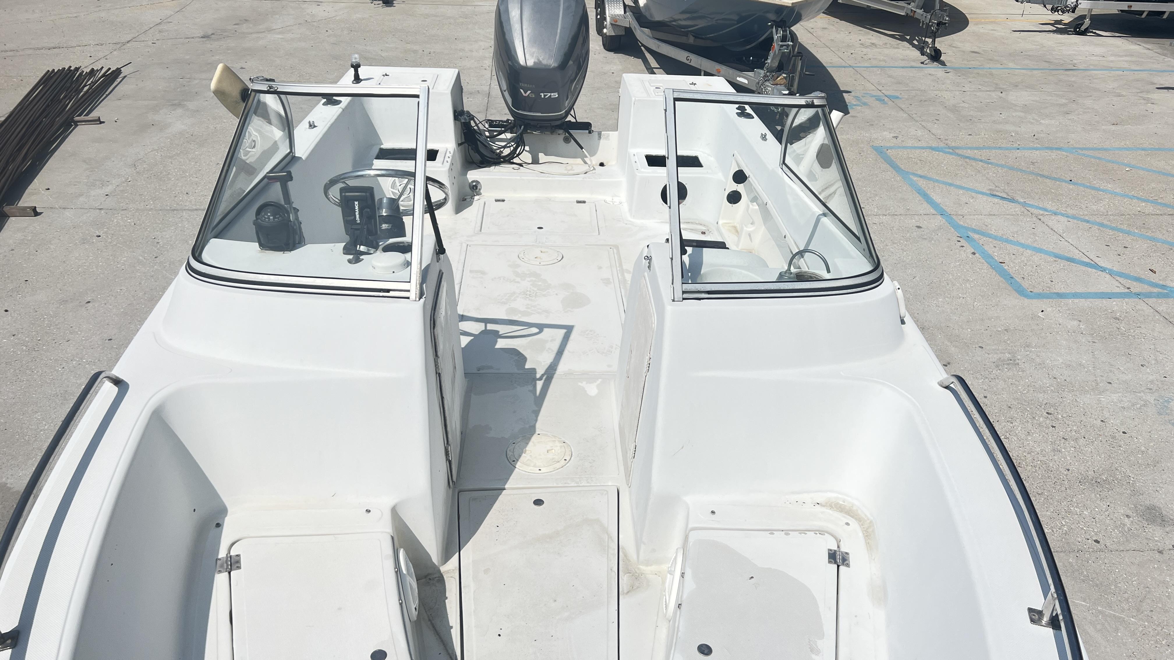 1998 Pro Sports Walk Through boat with open deck and windshield, parked on concrete.