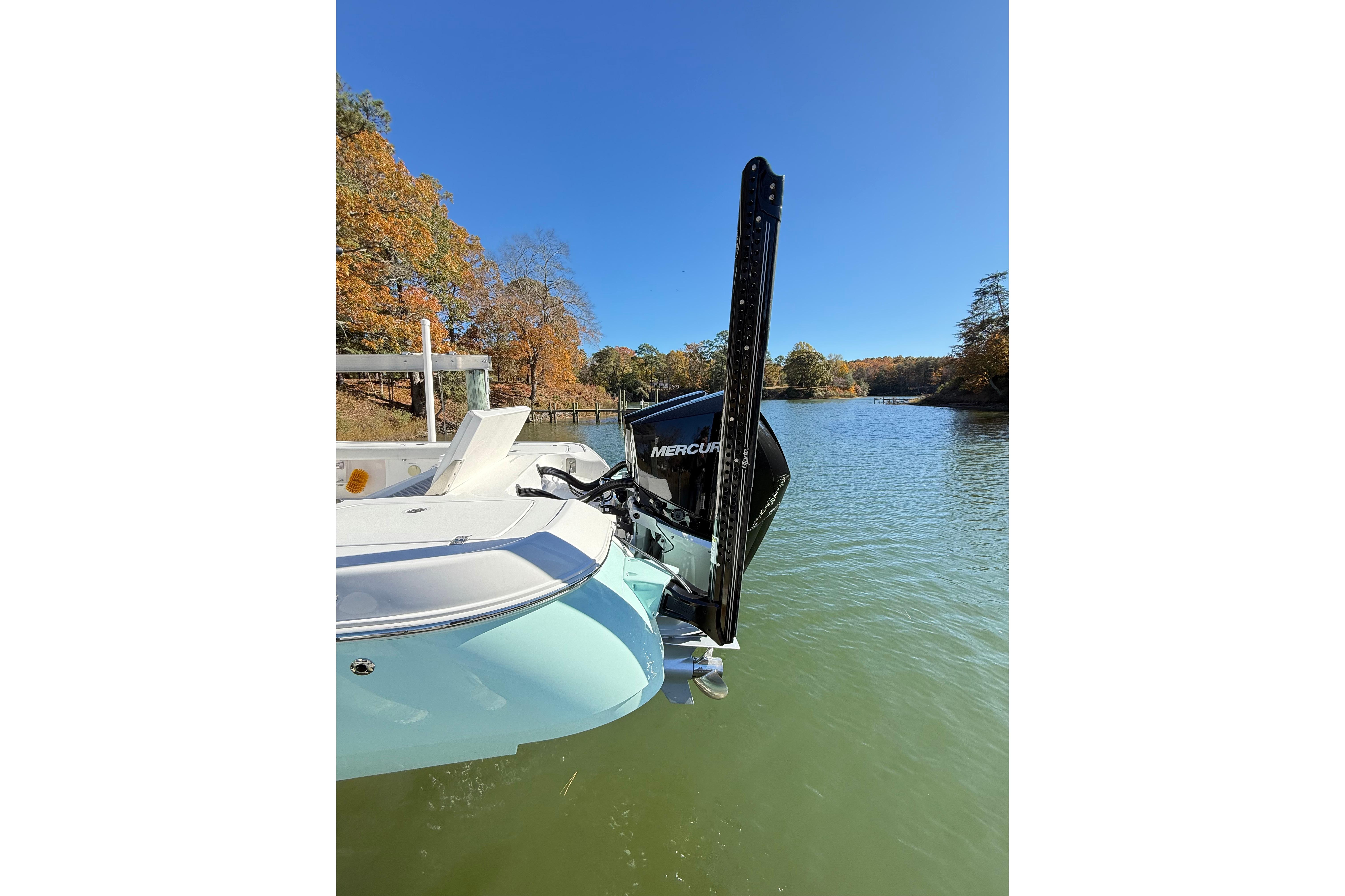 2023 Caymas 281 HB boat on a serene lake with autumn foliage.