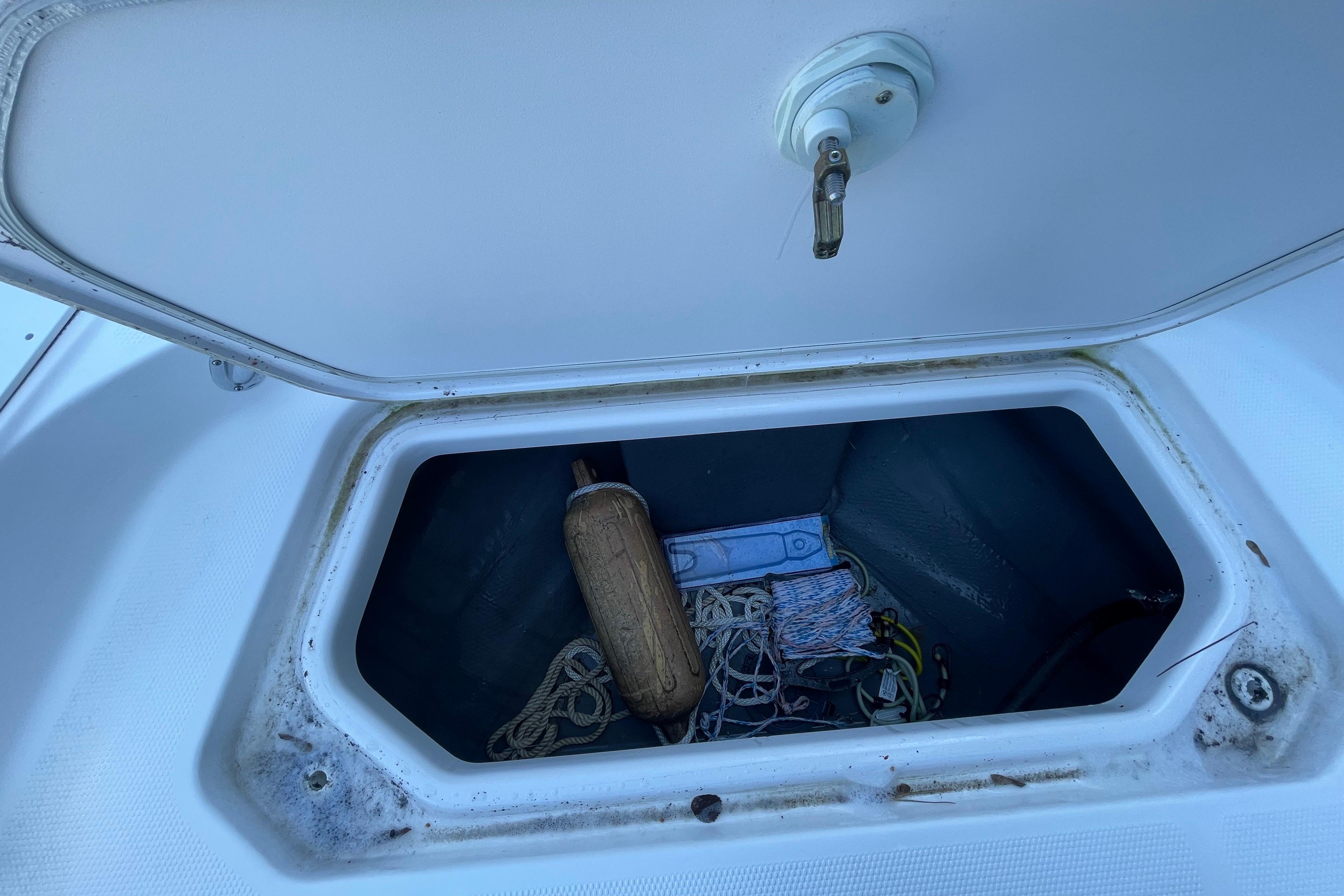 Open storage compartment on 2021 Yamaha Boats 195 FSH Sport, containing ropes and a fender.