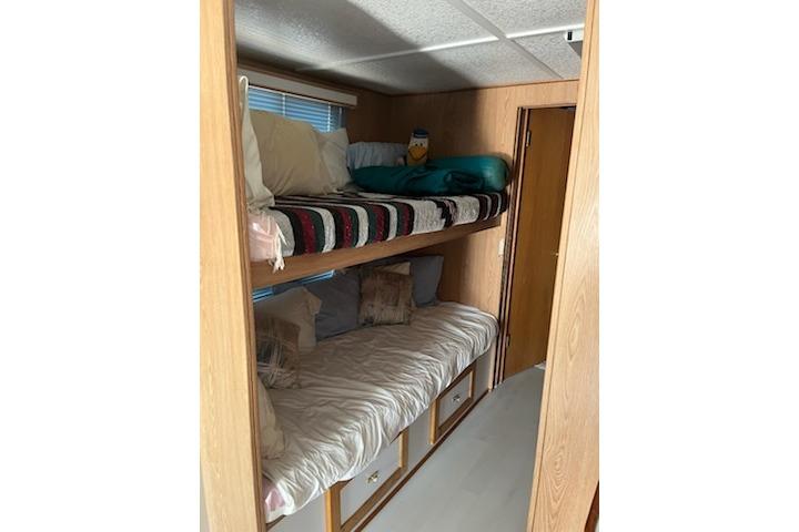 Bunk beds in a 1994 PlayCraft 5215, featuring cozy bedding and wooden interior.