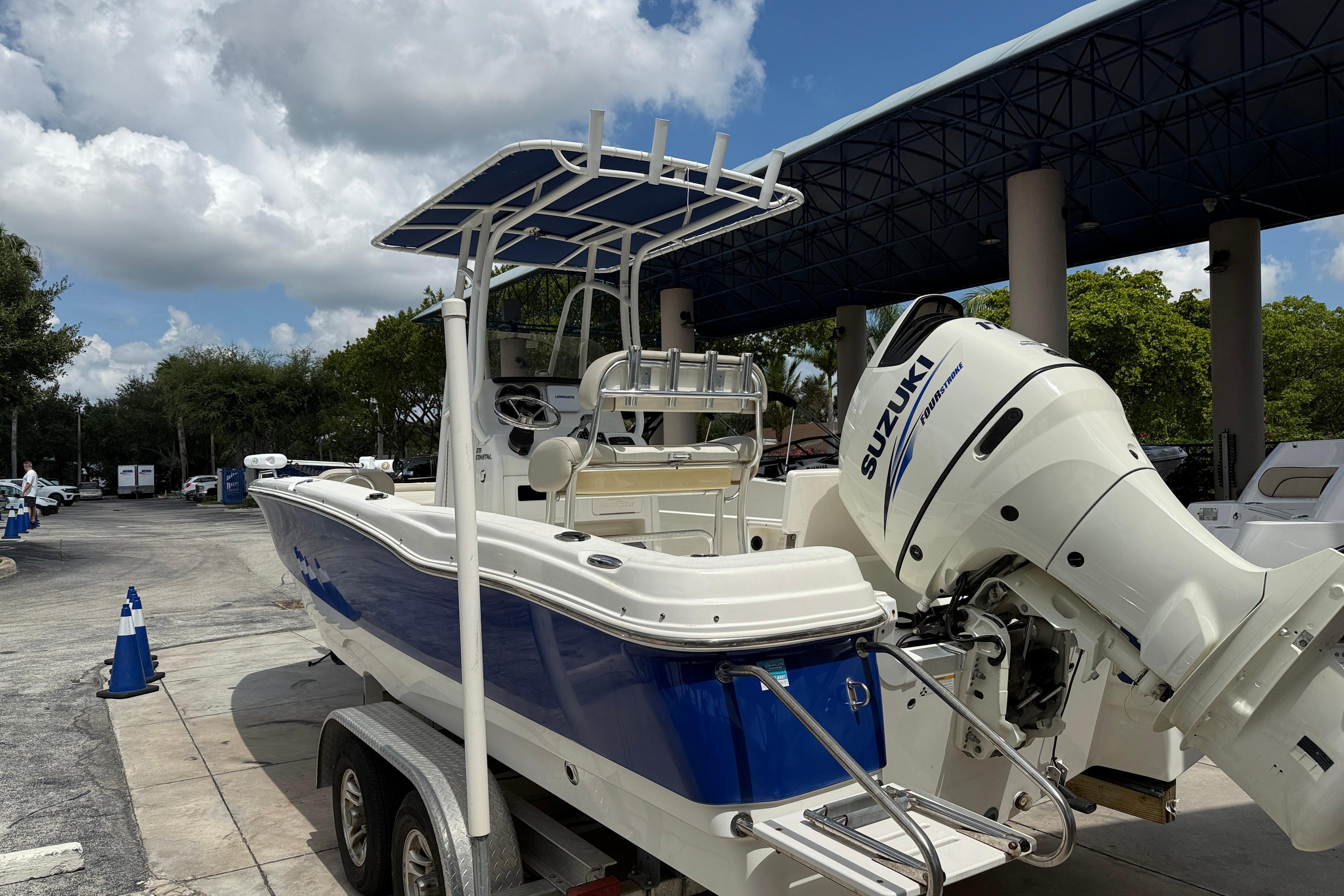 2015 NauticStar 231 Coastal boat with Suzuki engine on trailer, parked outdoors.