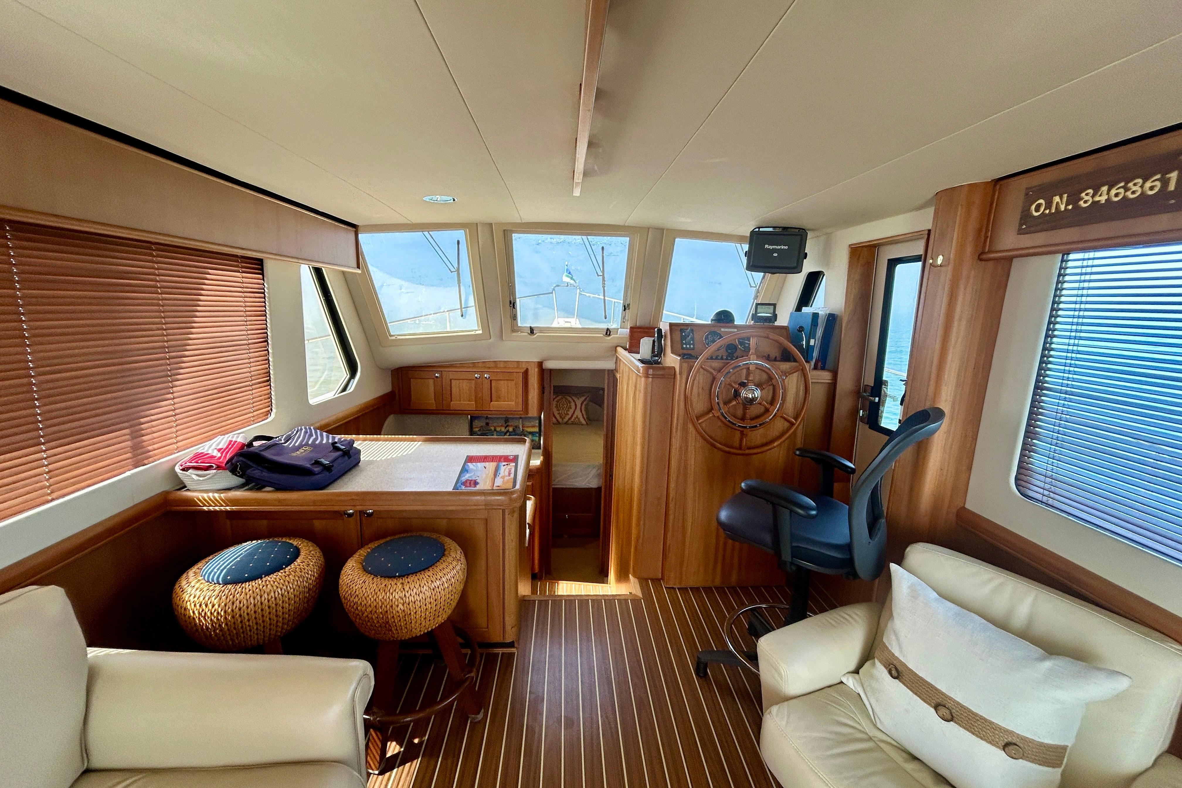 Interior of 2006 Mainship 34 Trawler with wooden helm, seating, and nautical decor.