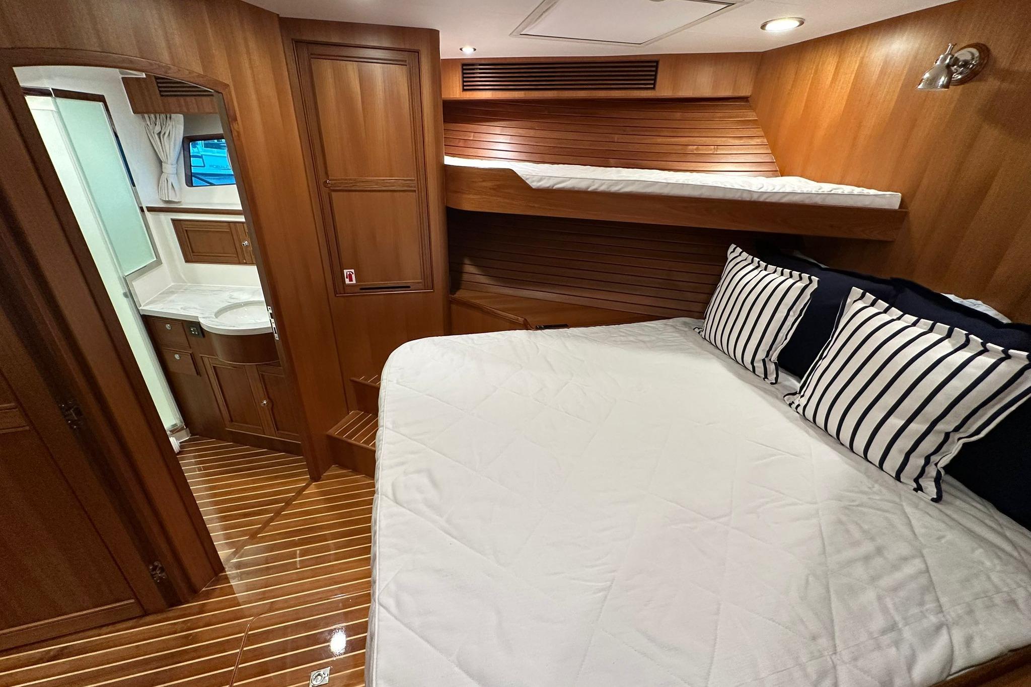 Luxurious cabin interior of 2023 Marlow Explorer 66E-CB yacht with wood finish and striped pillows.