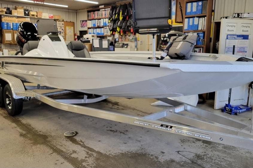2025 Xpress H20C Crappie boat on trailer in a workshop setting.