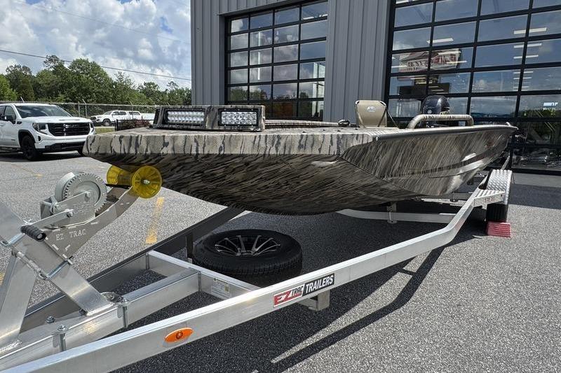 2026 Excel 183 Tomahawk boat on trailer, parked outside a building.