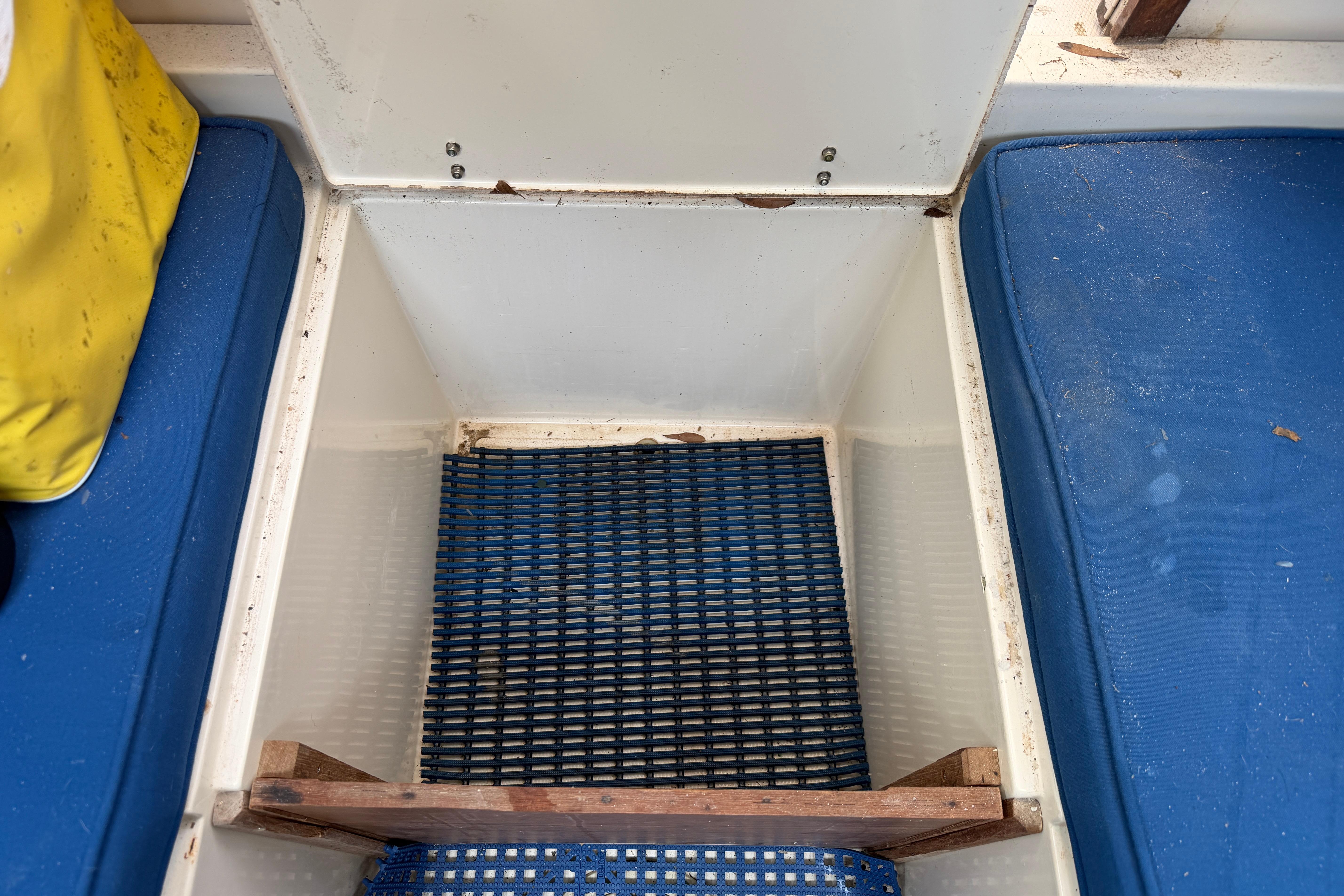 Storage compartment on a 1987 Grady-White Seafarer 226 boat with blue cushions.