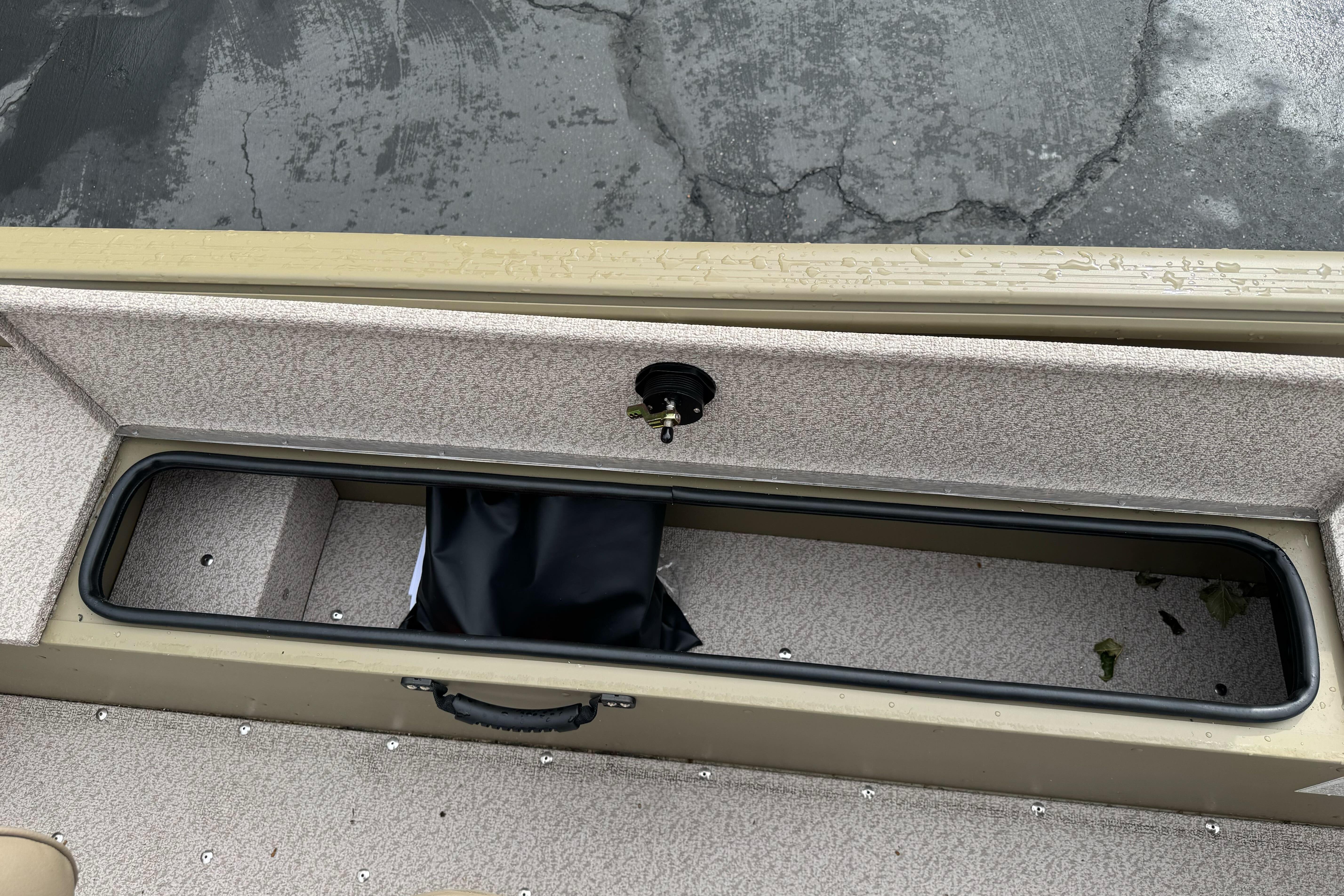 2026 Lund 2075 Alaskan SS boat storage compartment with black bag, wet surface.