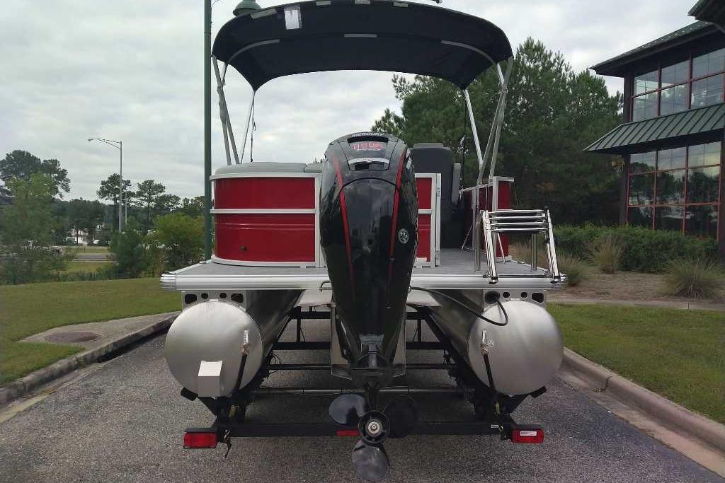 2026 Sun Tracker Party Barge 20 DLX pontoon boat with outboard motor, parked outdoors.