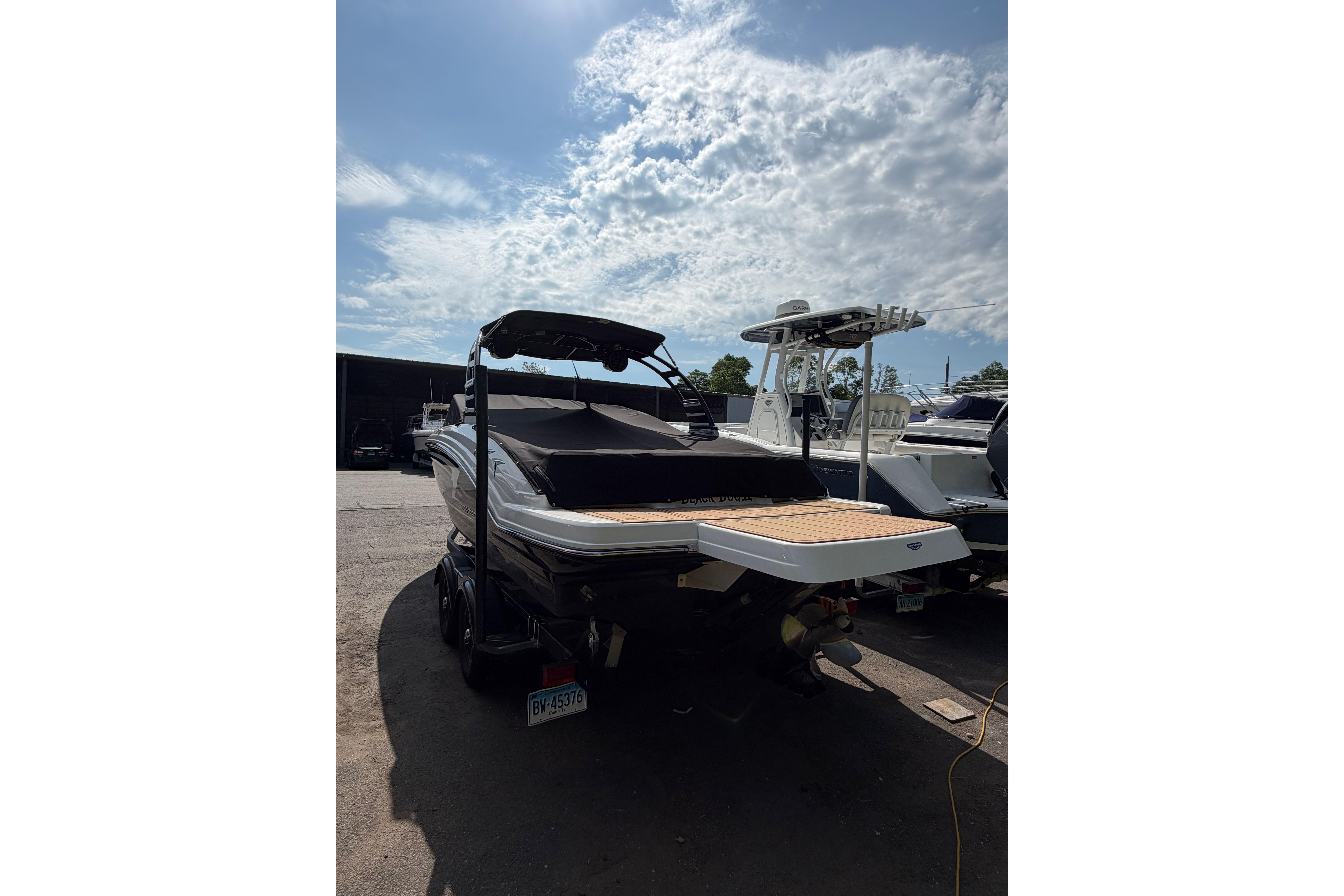 2025 Chaparral 230 SSi boat with sleek design, parked outdoors under a cloudy sky.