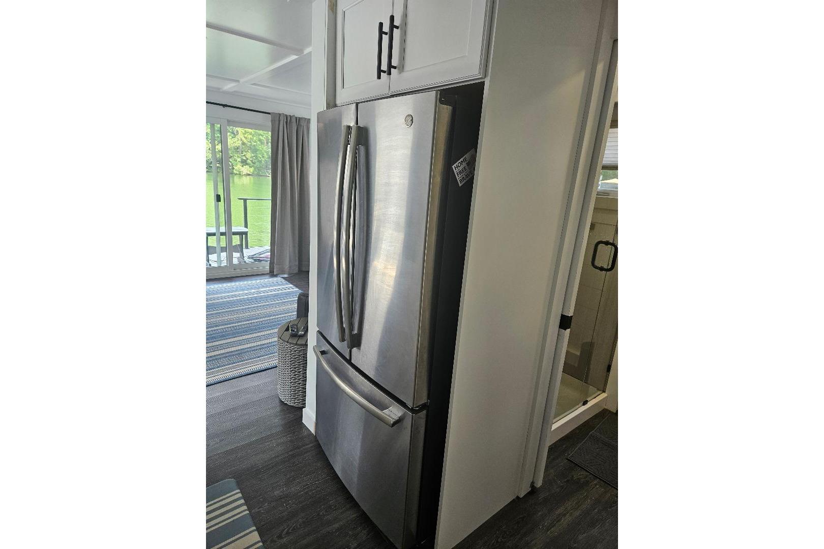 Modern kitchen interior of 2021 East Coast Houseboats Freedom 40, featuring stainless steel refrigerator.