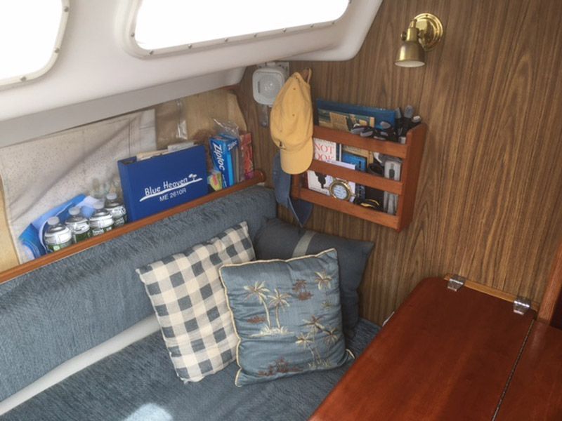 Interior of a 1975 O'Day Sloop with cozy cushions and wooden shelf.