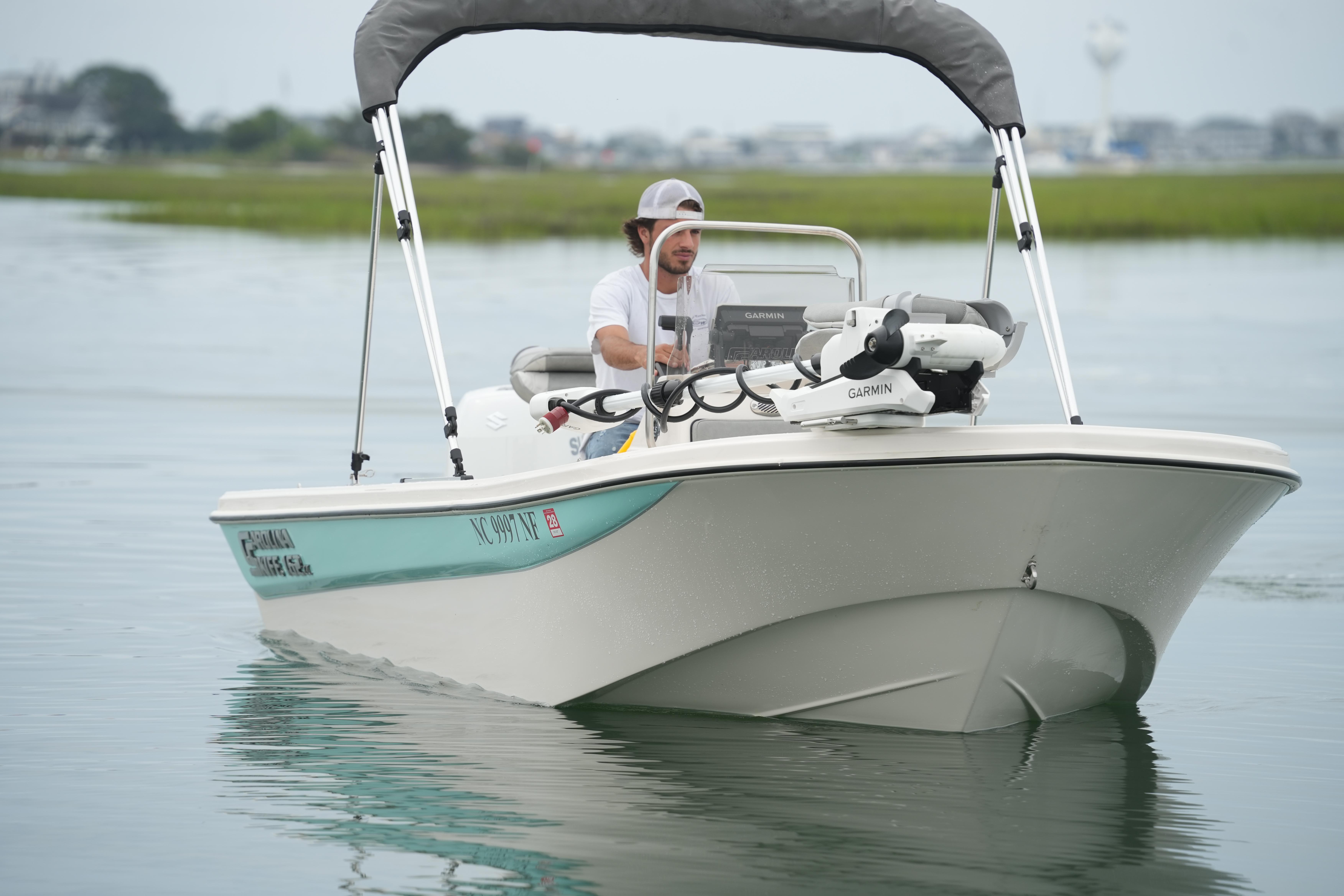 2025 Carolina Skiff 162 JLS boat cruising on calm water with a canopy and Garmin equipment.