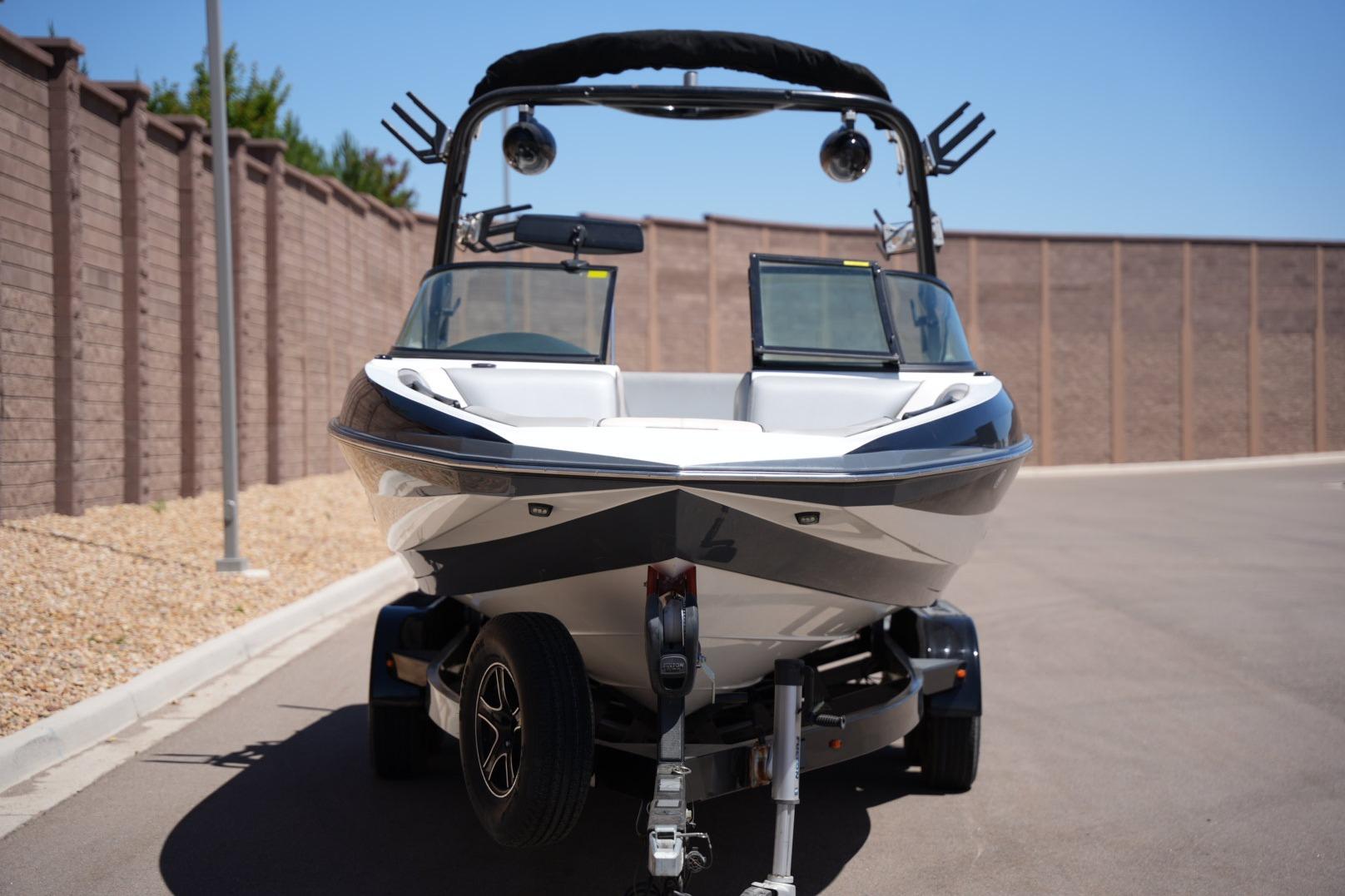 2016 Supreme S211 boat on trailer, parked on a sunny street.