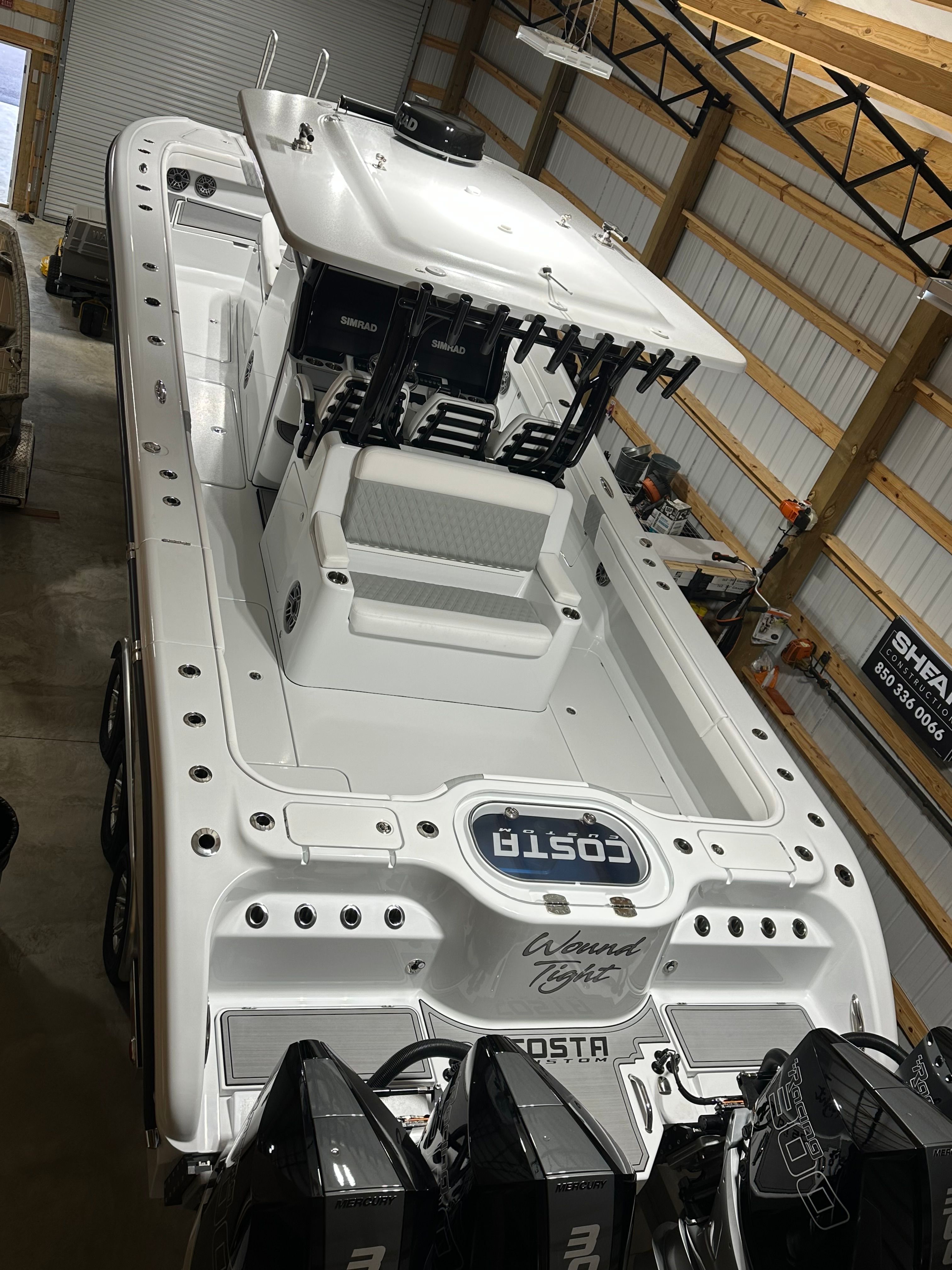 A white boat with multiple engines is inside a warehouse.