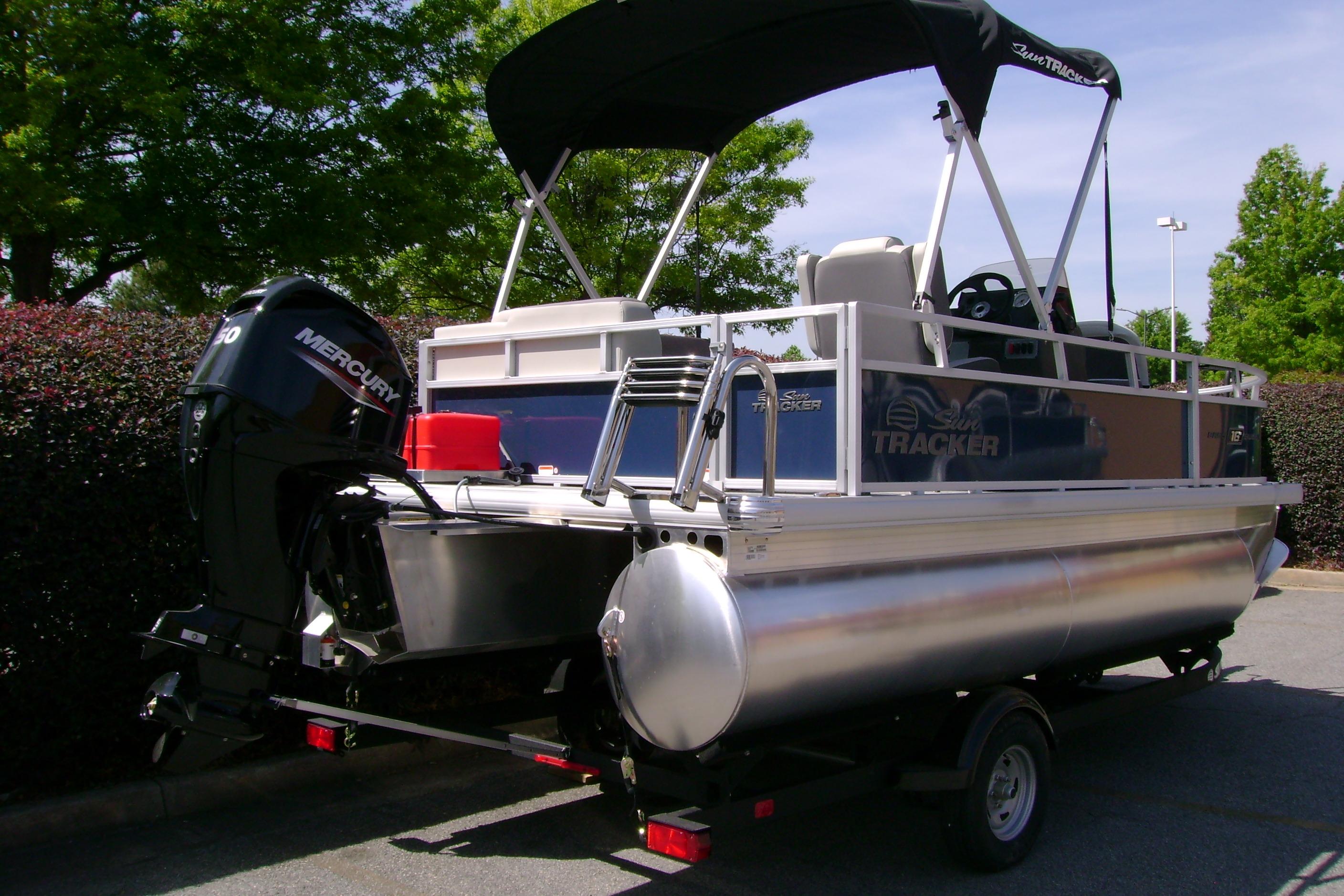 2026 Sun Tracker Bass Buggy 16 XL Select pontoon boat with Mercury engine, parked outdoors.