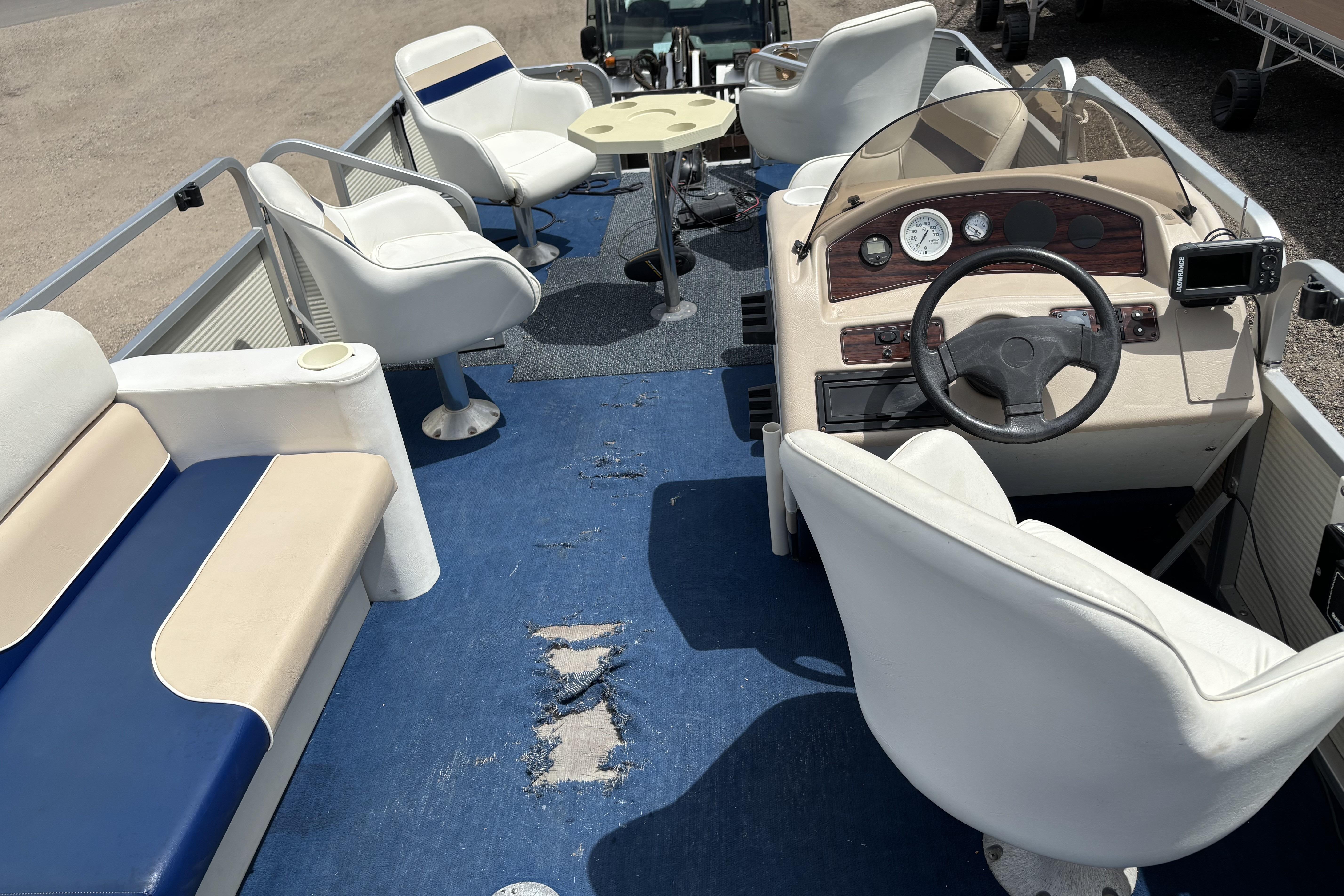 1997 Northwood 24' Pontoon boat interior with worn blue carpet and white seating.