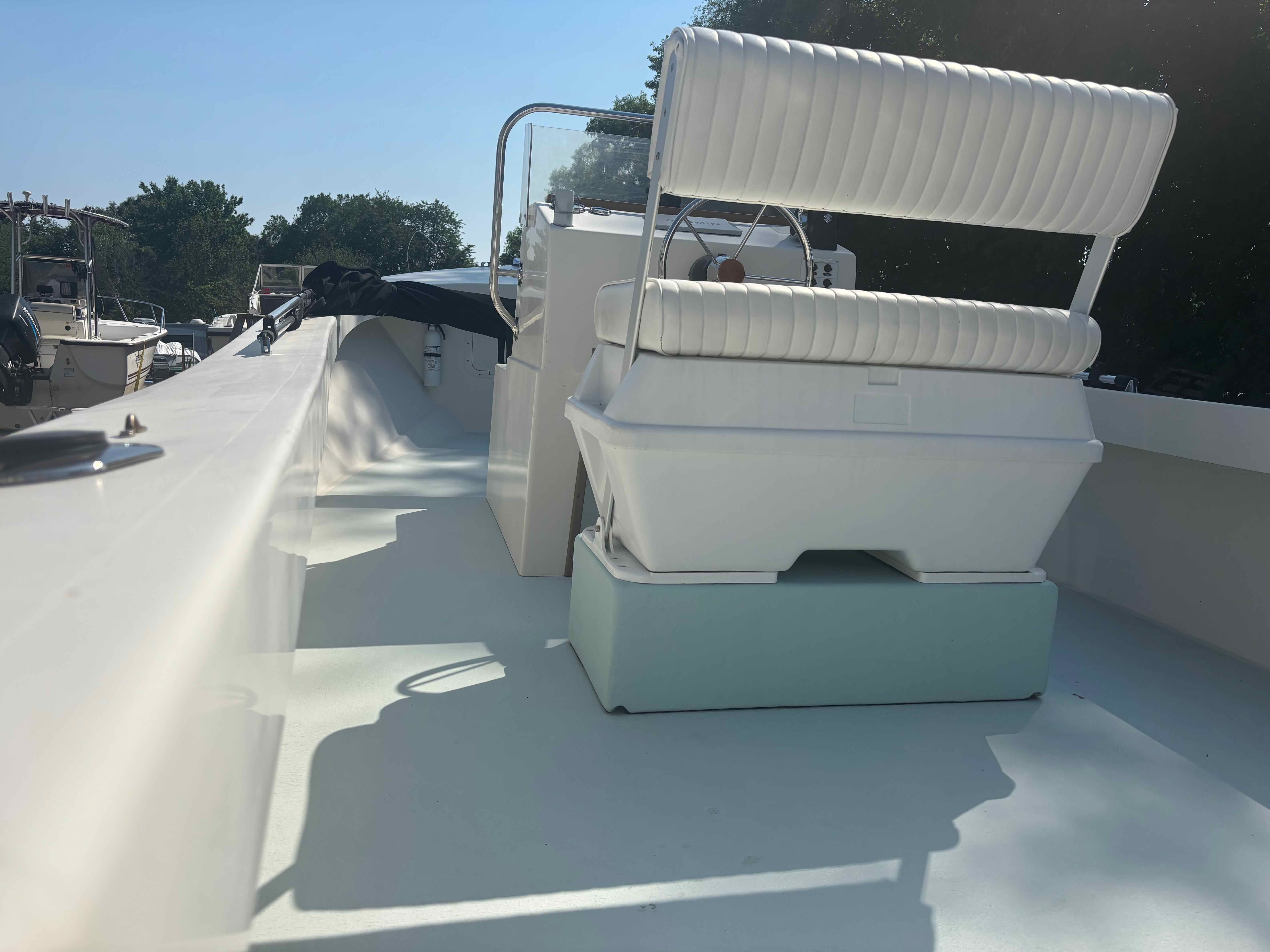 A 2016 Surfside 21 Center Console boat with a white seat and steering console.