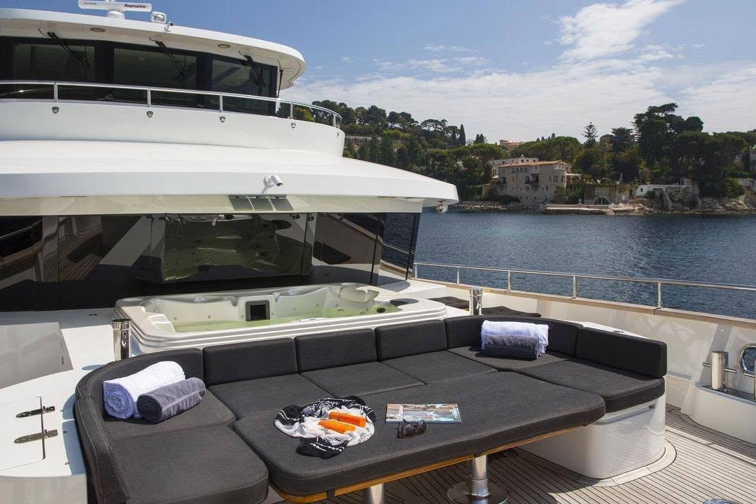 Luxurious 2014 Fifth Ocean Yachts Explorer with deck seating and jacuzzi, overlooking serene coastal scenery.