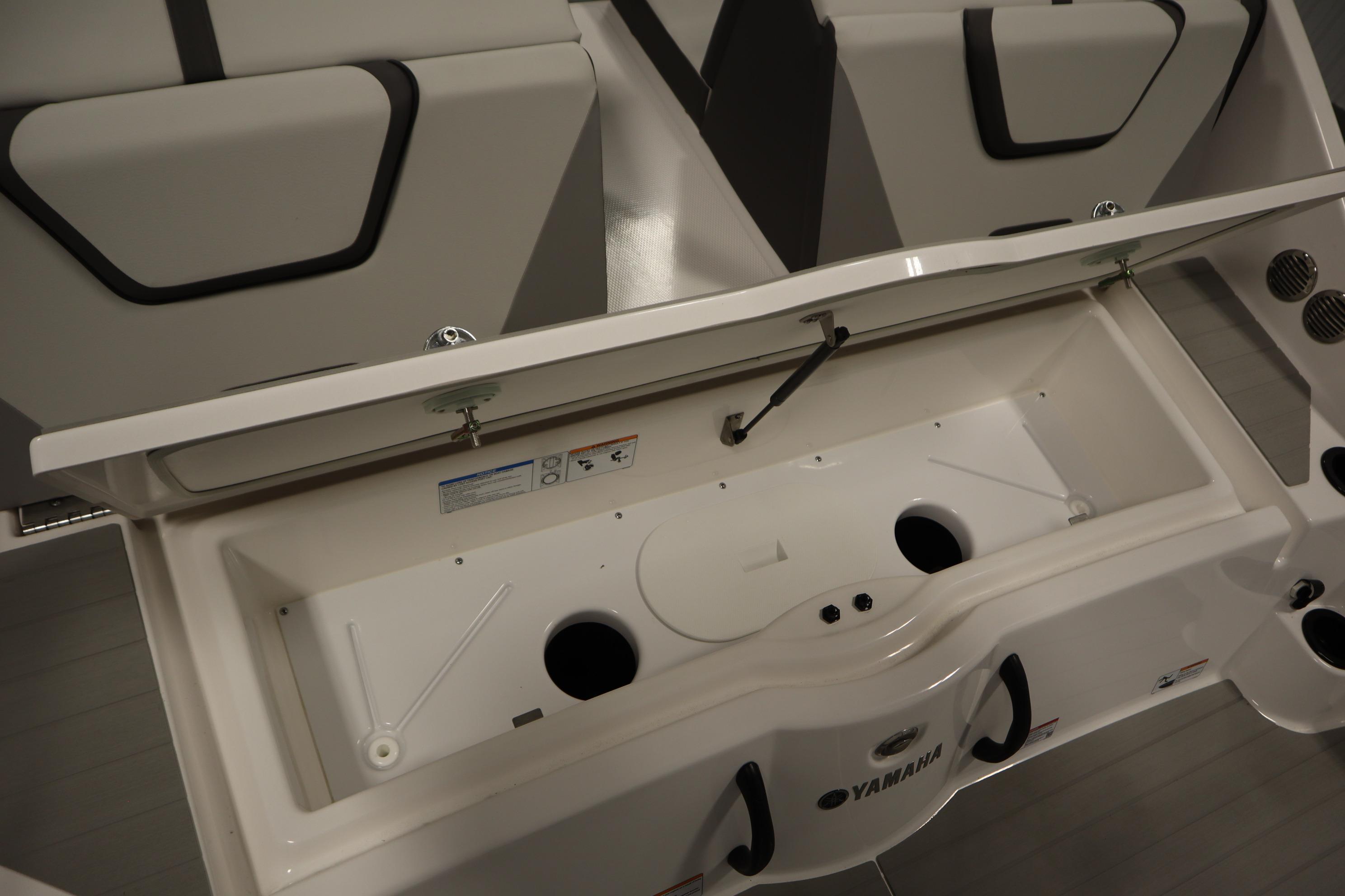 2026 Yamaha Boats AR220 storage compartment with open lid, showcasing interior design.