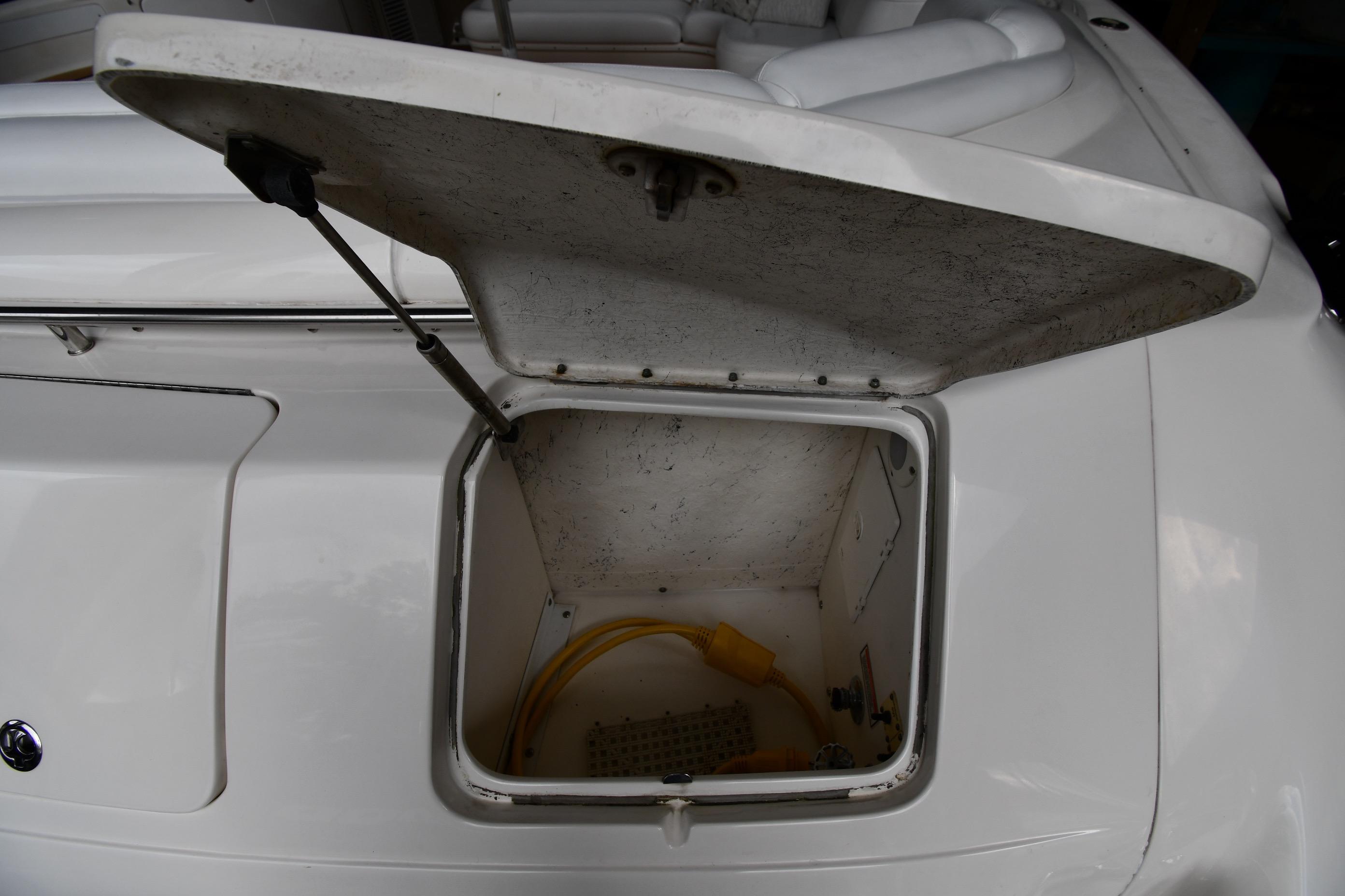 Open storage compartment on 2001 Sea Ray 540 Sundancer boat, showing interior and yellow cable.