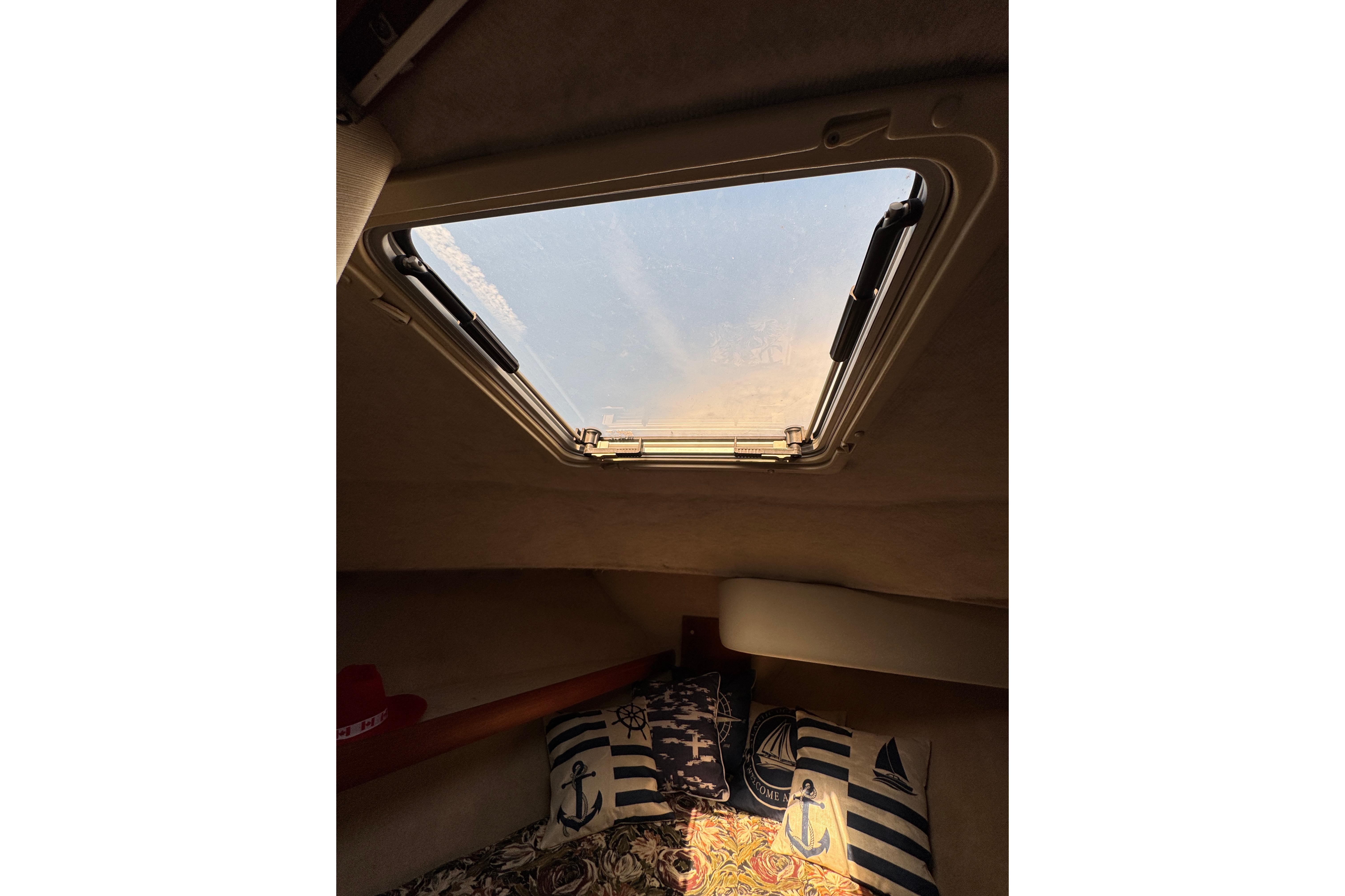 Interior view of 1995 Bayliner 3288 Motoryacht cabin with nautical-themed pillows and skylight.