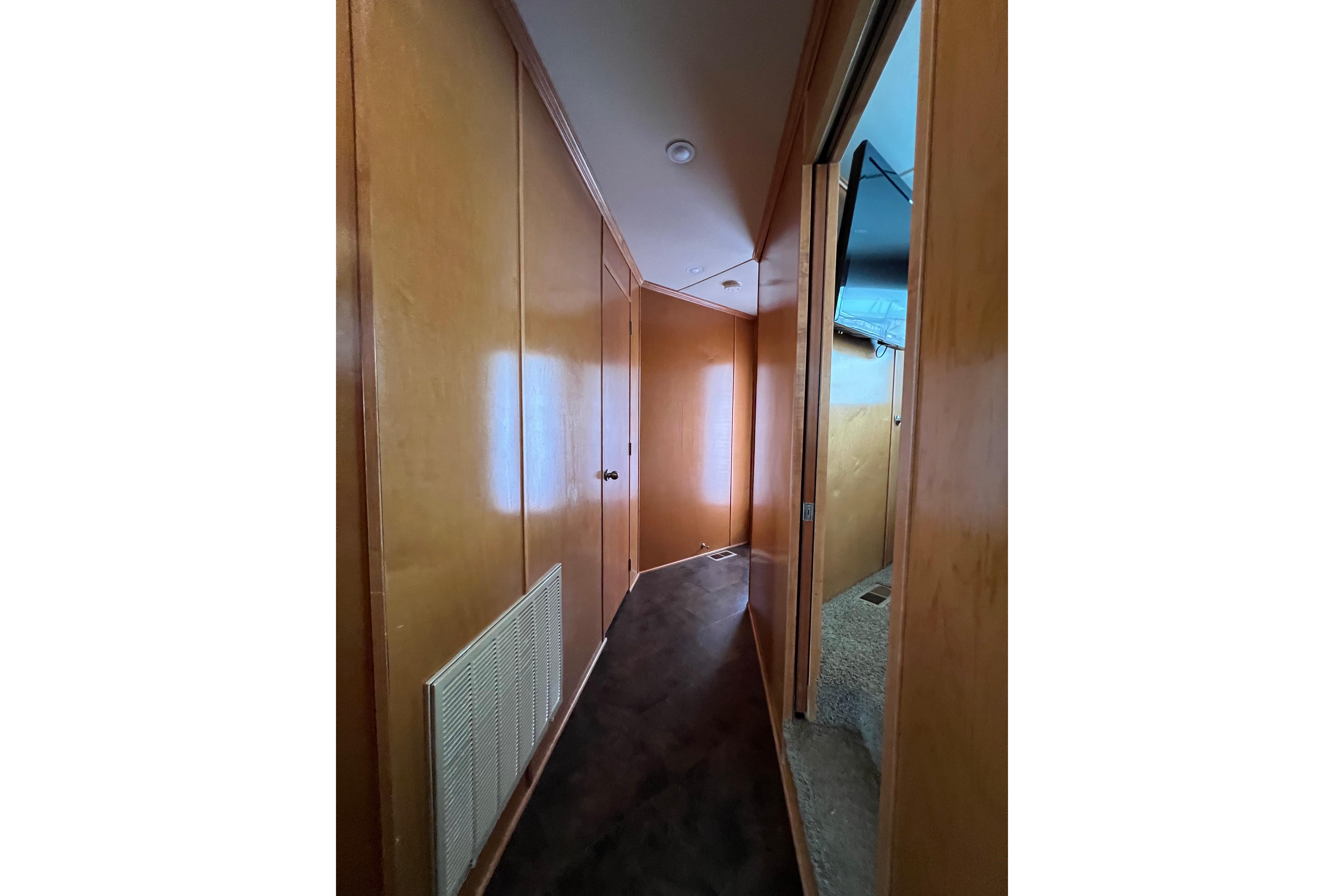 Narrow hallway inside 2013 Destination Yacht Lotta Yachta, featuring wooden paneling and carpeted flooring.