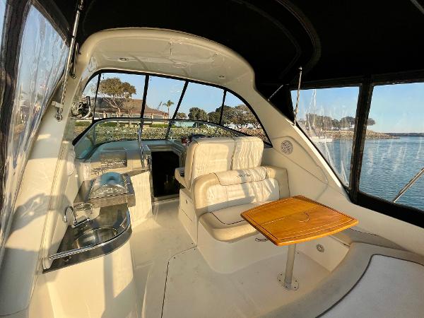 2014 Sea Ray 330 Sundancer interior with seating, table, and helm, overlooking serene waters.