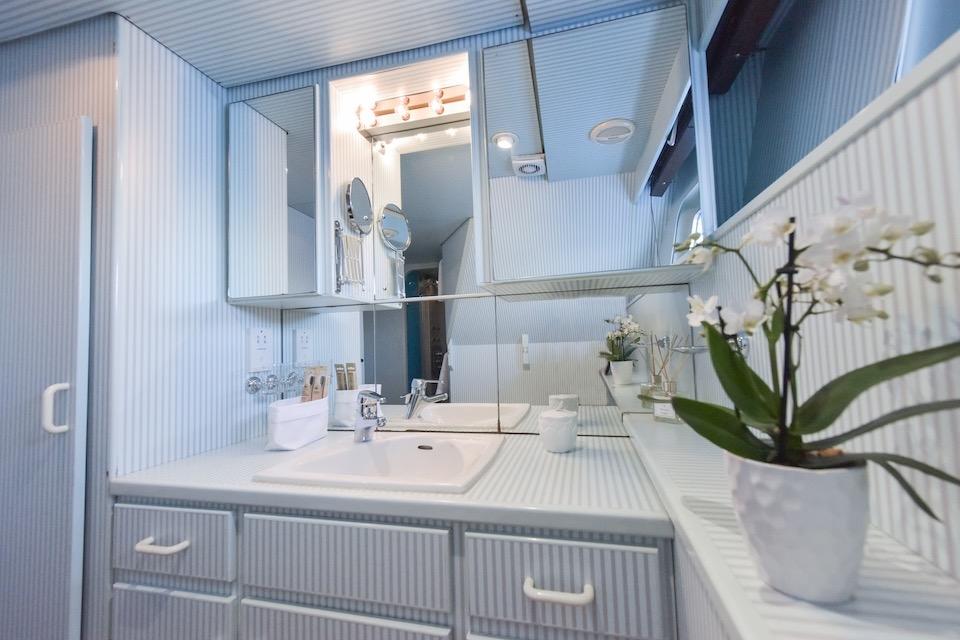Modern bathroom with white fixtures, mirrors, and decorative orchids on a W.A. Souter & Sons 1984 model.
