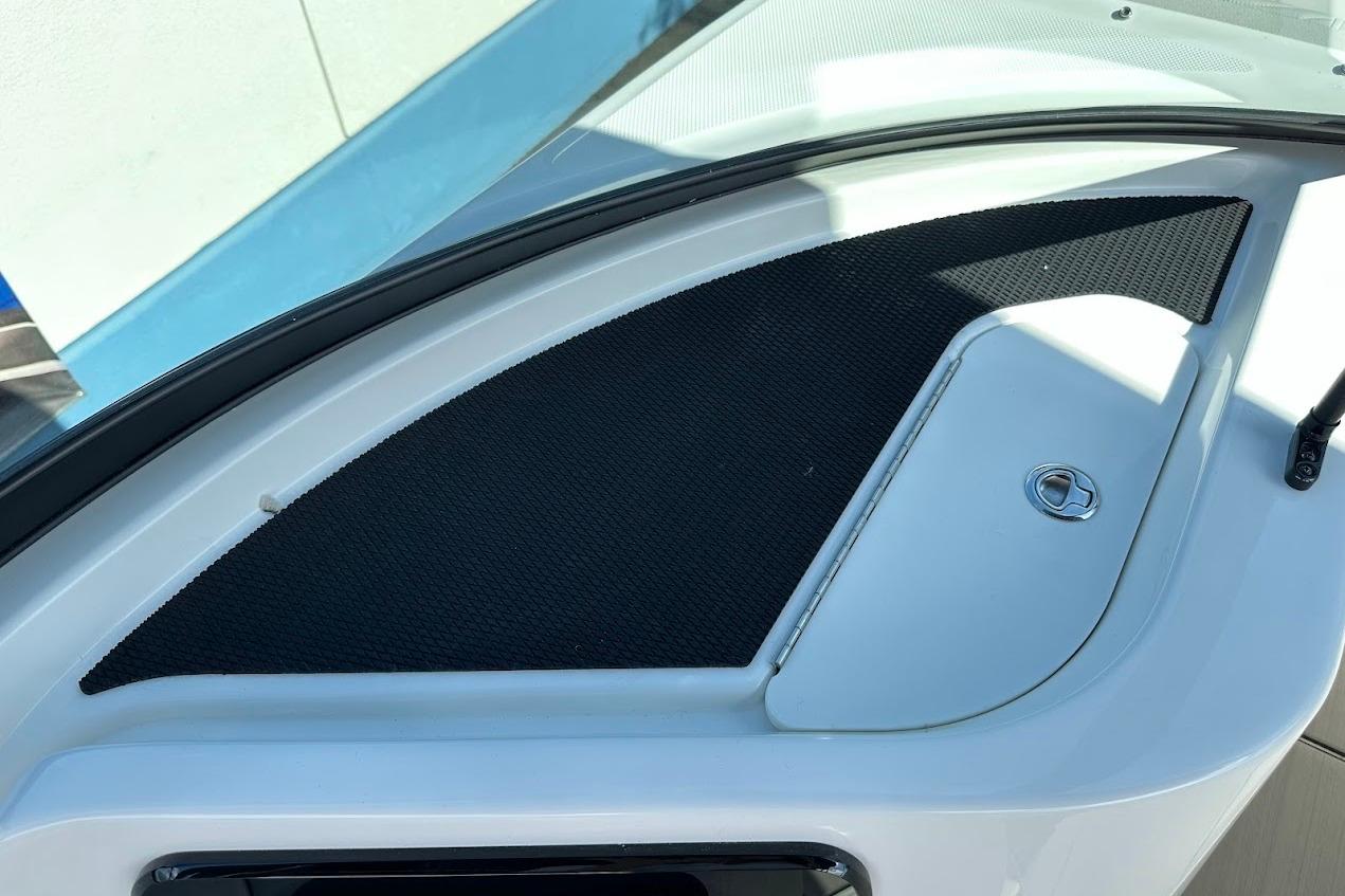 2026 Sea Ray SDX 230 Surf boat dashboard with storage compartment and black mat.