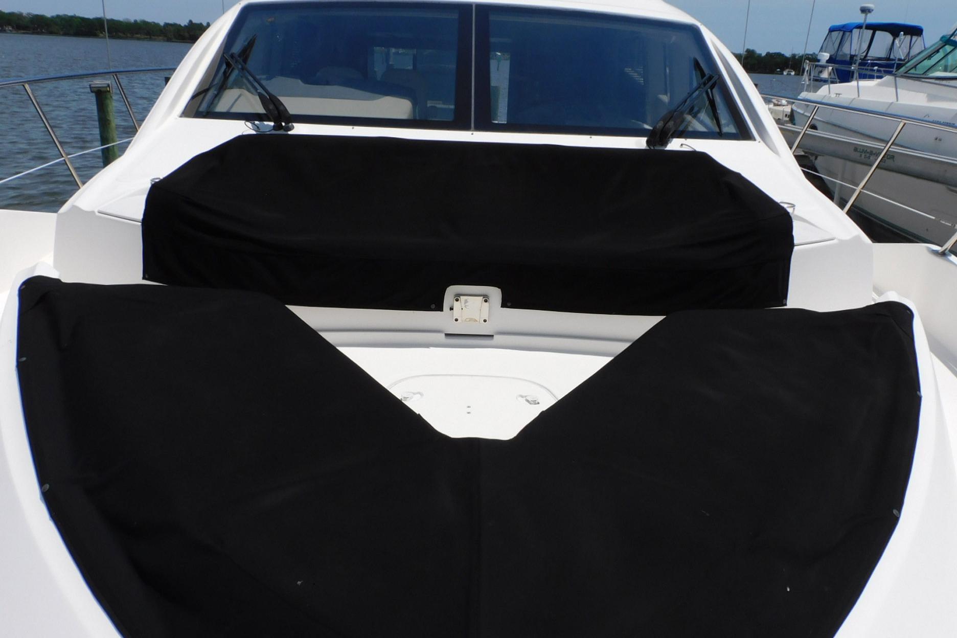 2019 Sea Ray L550 yacht with black covers on deck, docked by the water.