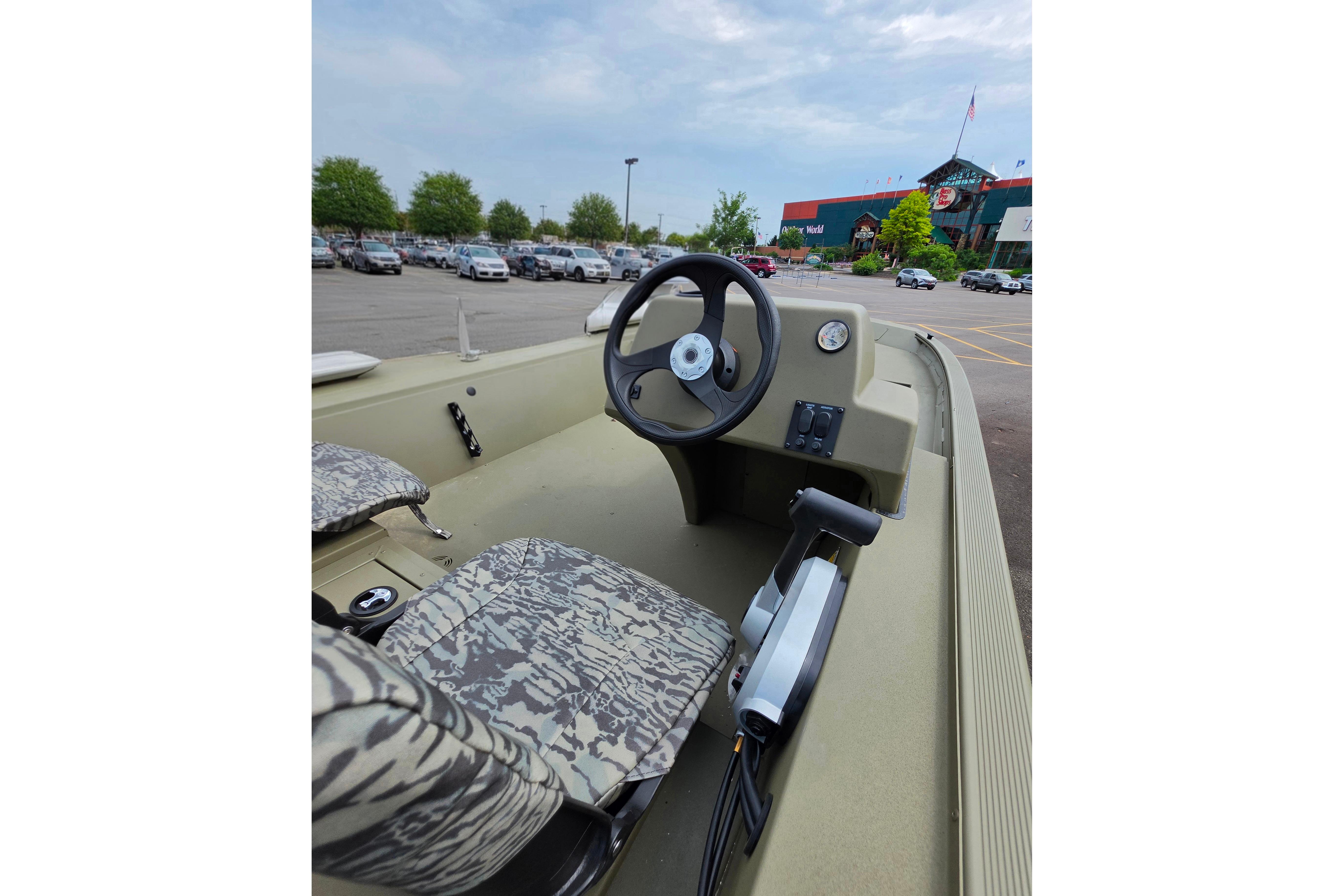 2026 Tracker Grizzly 1754 SC boat interior with camouflage seats in a parking lot.