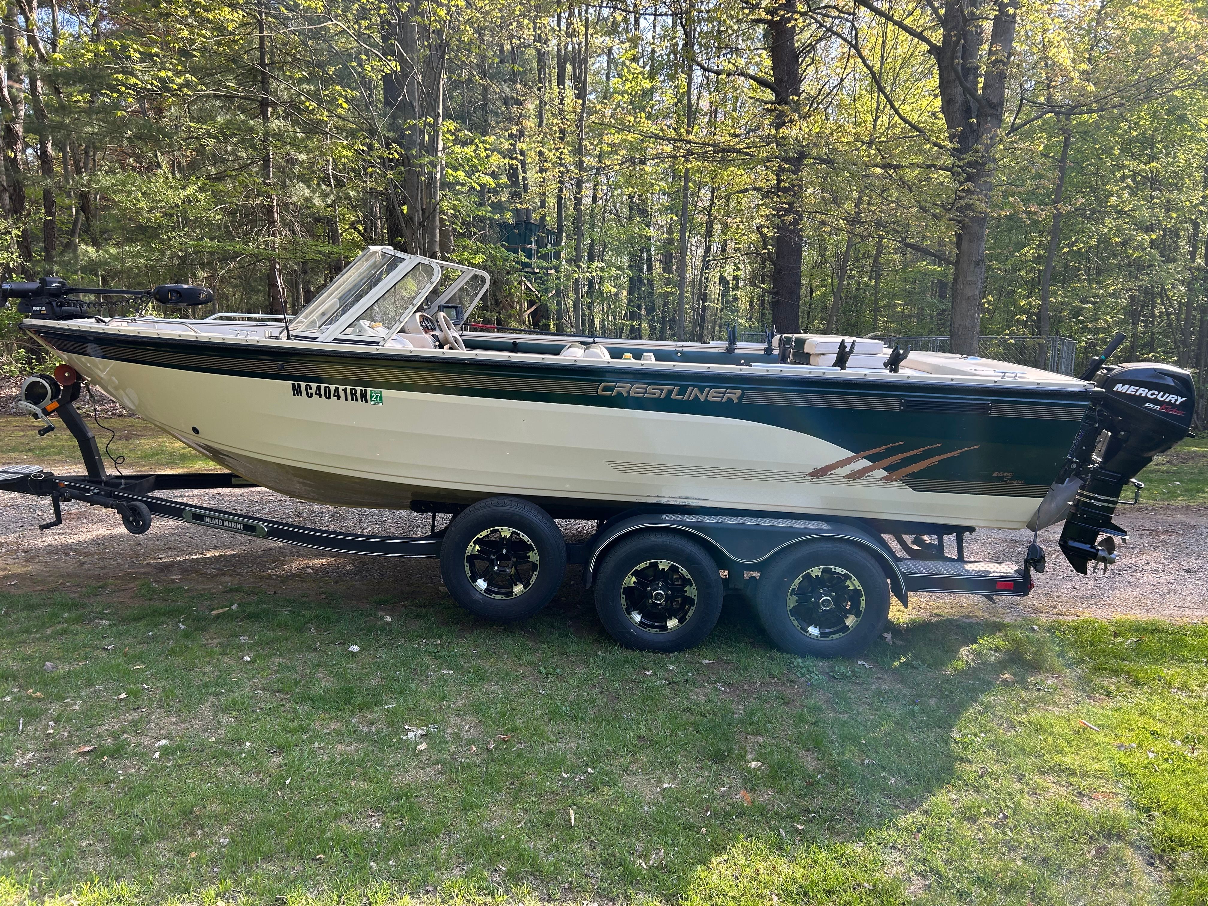 1997 Crestliner 2050 Sportfish boat parked in a wooded area.