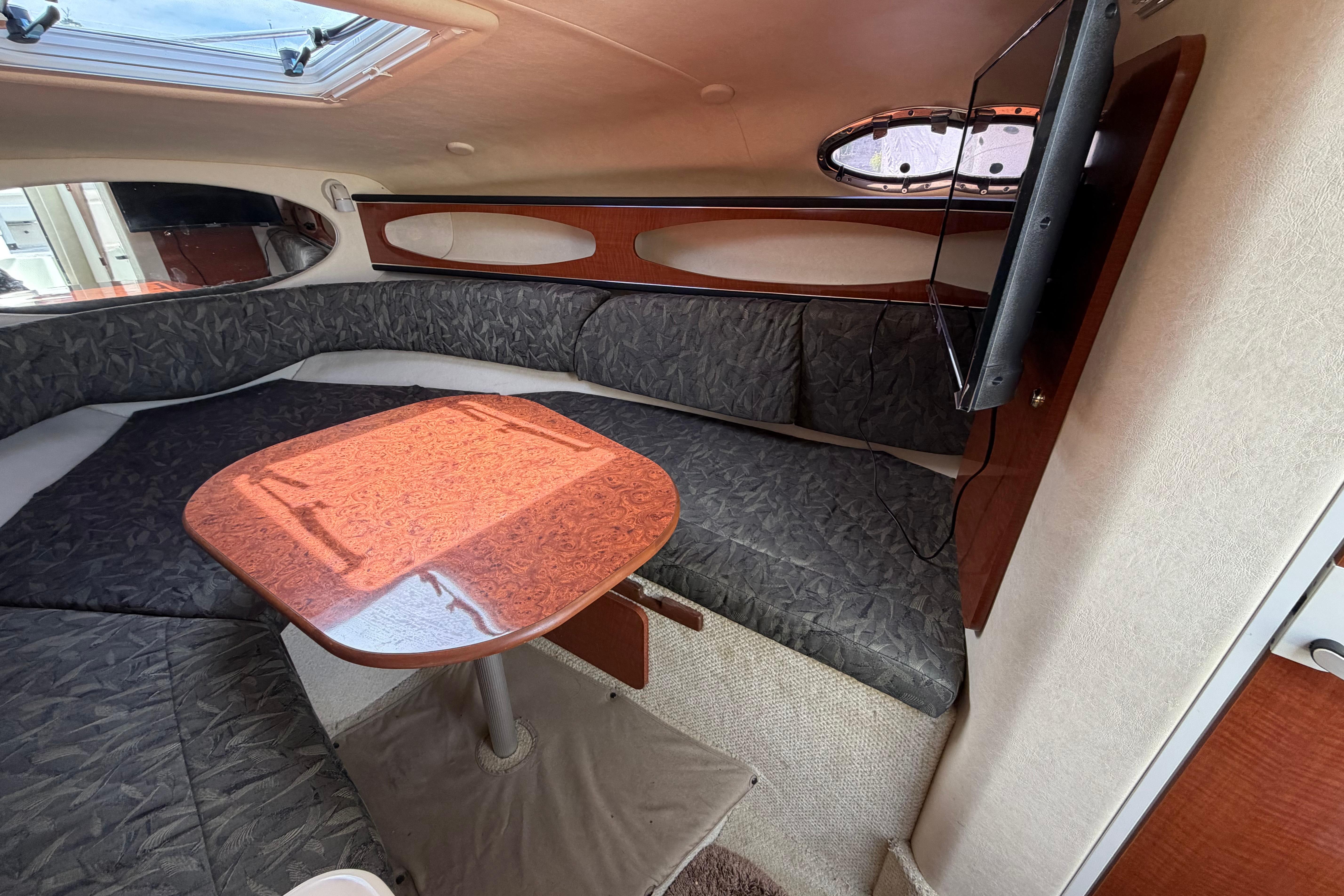 Interior of 2004 Sea Ray Sundancer 260 with cozy seating and wooden table.