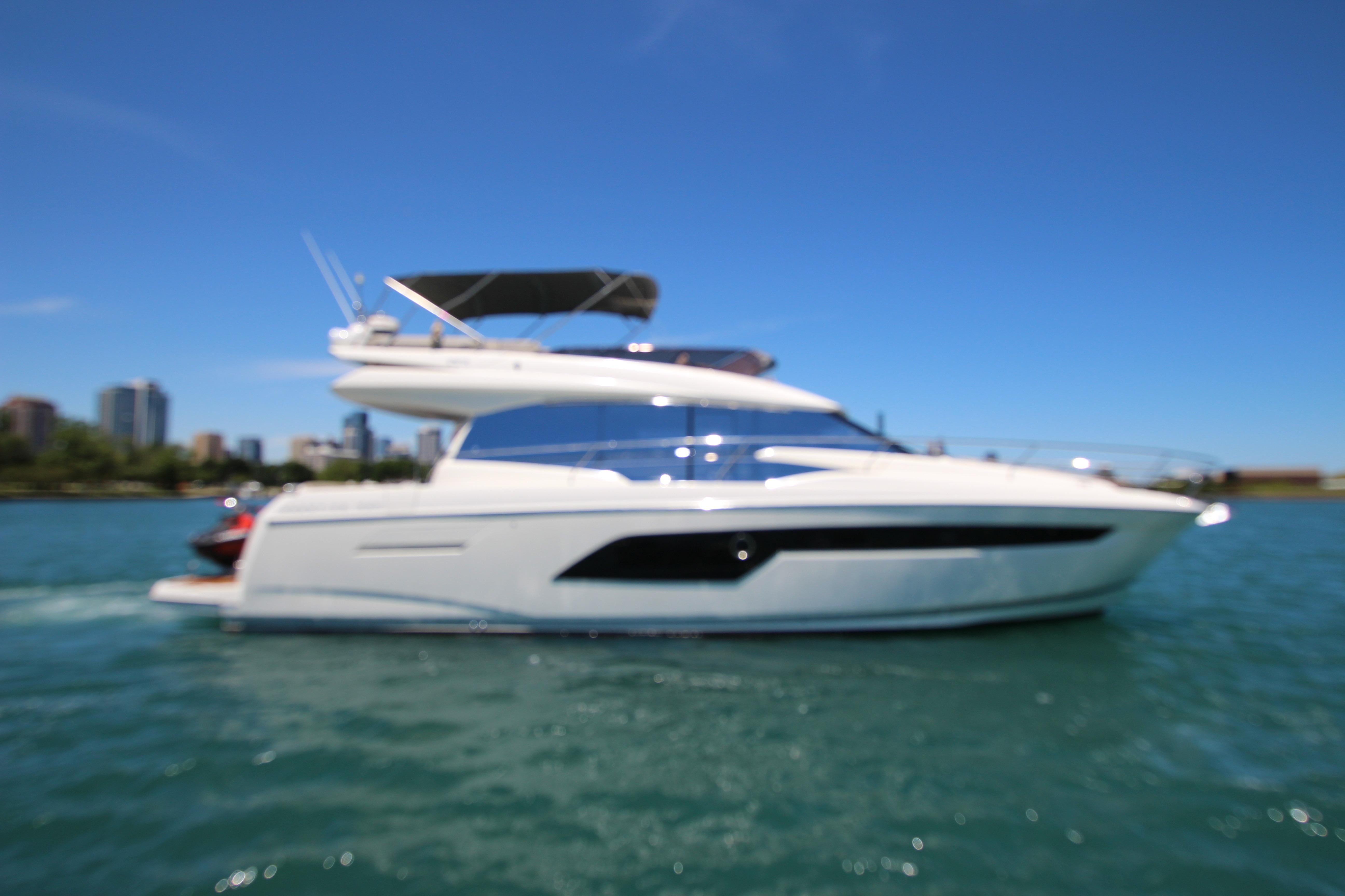 Blurry image of a 2022 Prestige 520 yacht on water under a clear blue sky.