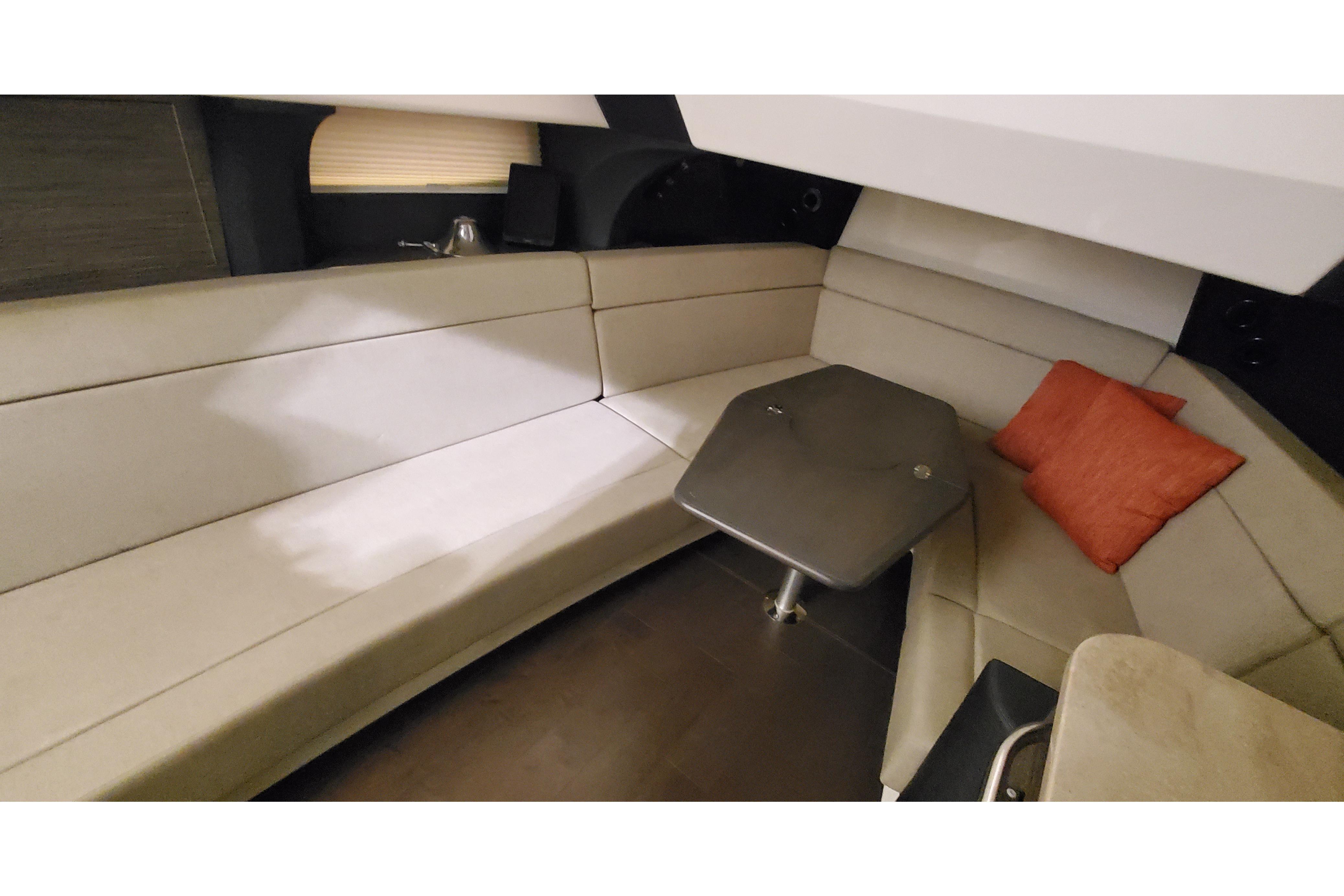 2016 Boston Whaler 420 Outrage cabin interior with beige seating and table.