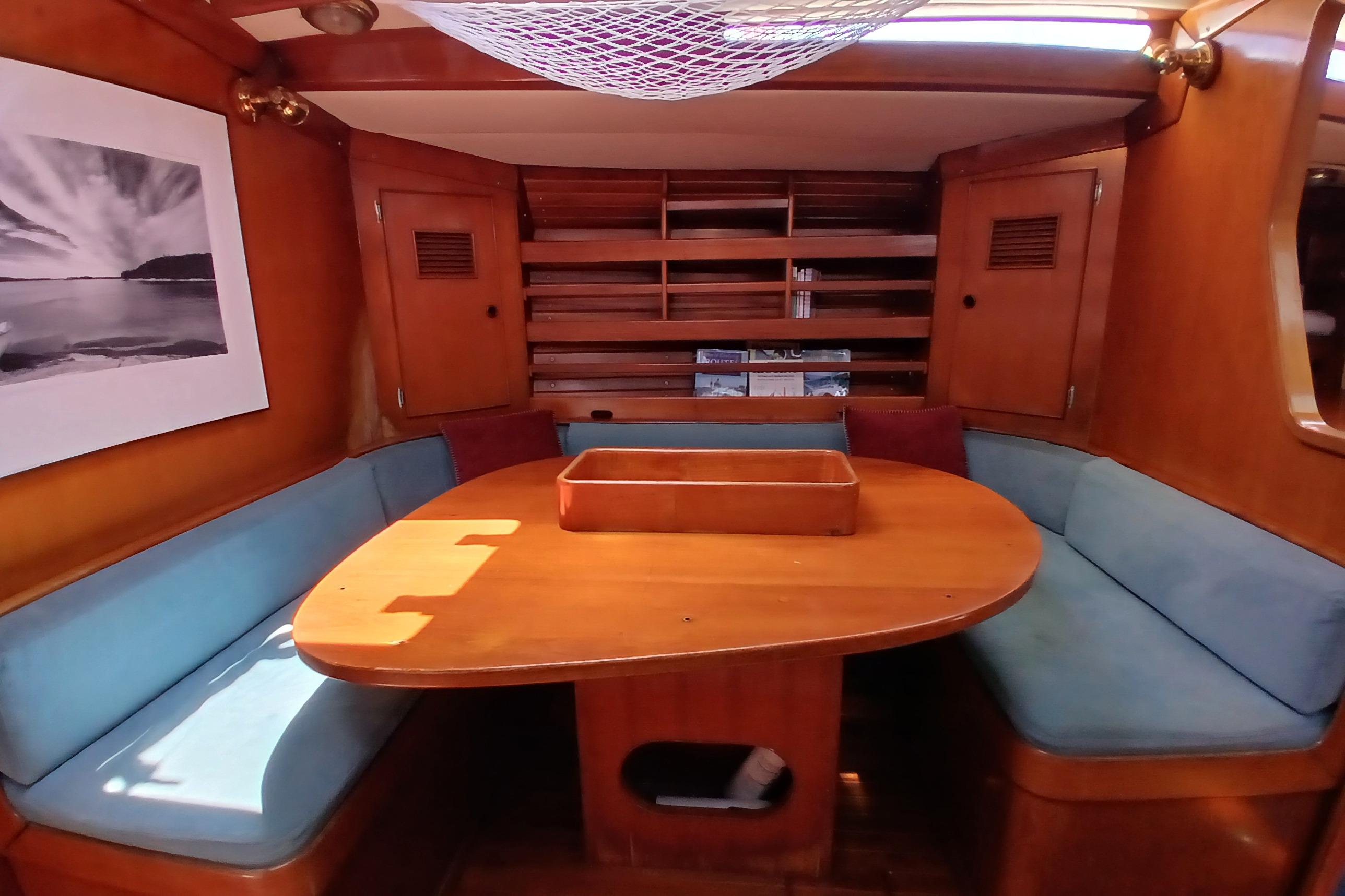 Cozy 1981 SKYE 51 yacht interior with wooden dining area and blue seating.