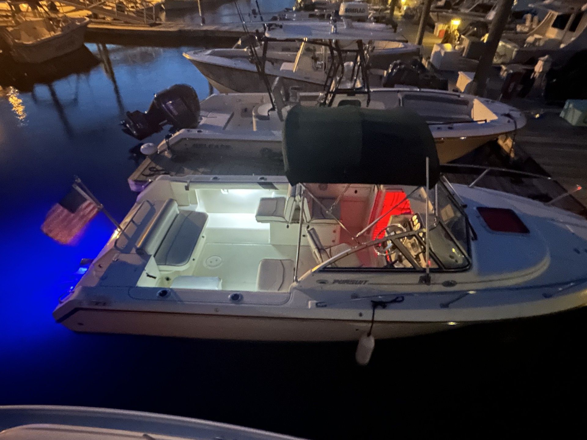 1999 Pursuit Denali boat docked at night with lights on.