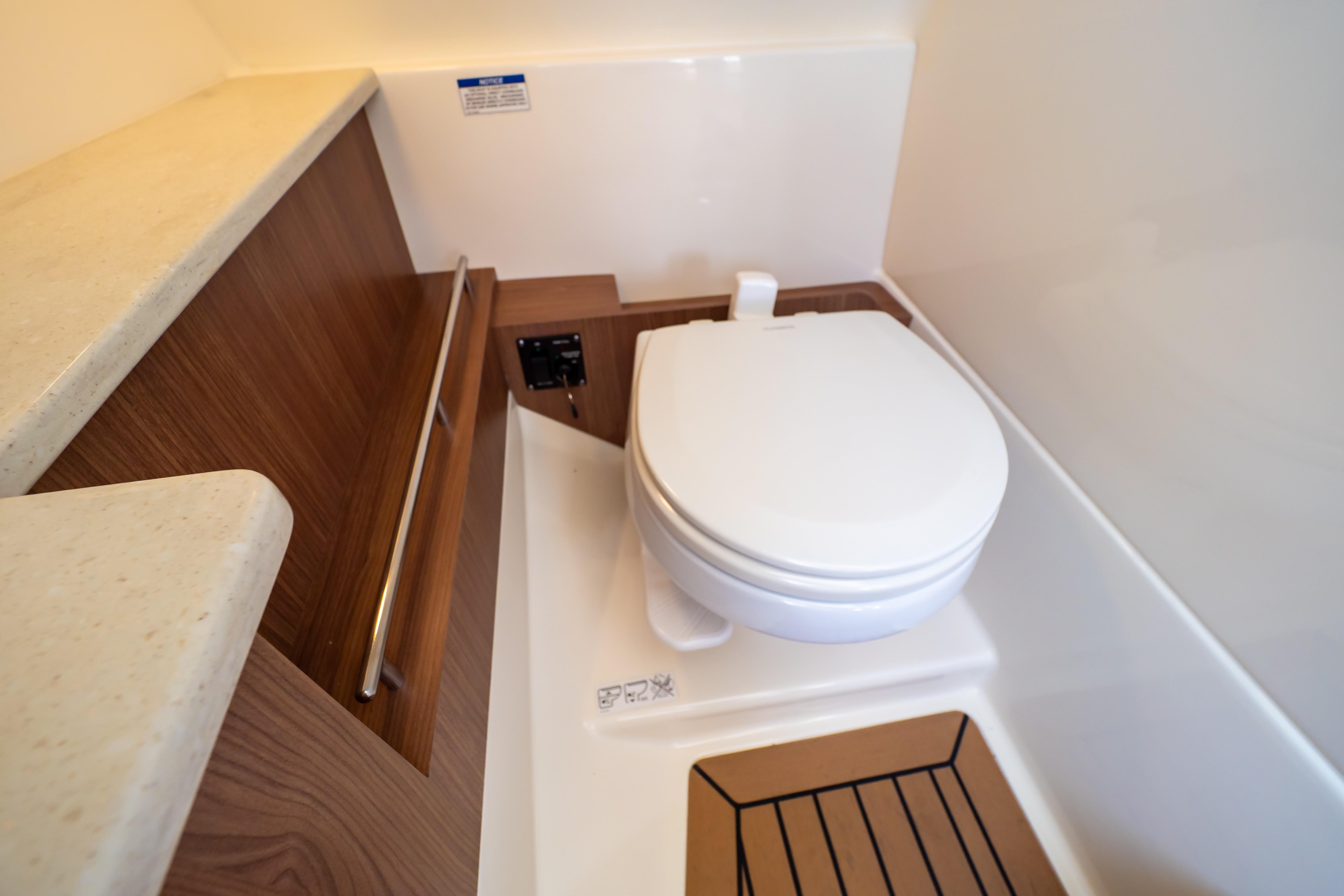 2019 Boston Whaler 270 Vantage boat bathroom with toilet and wooden accents.