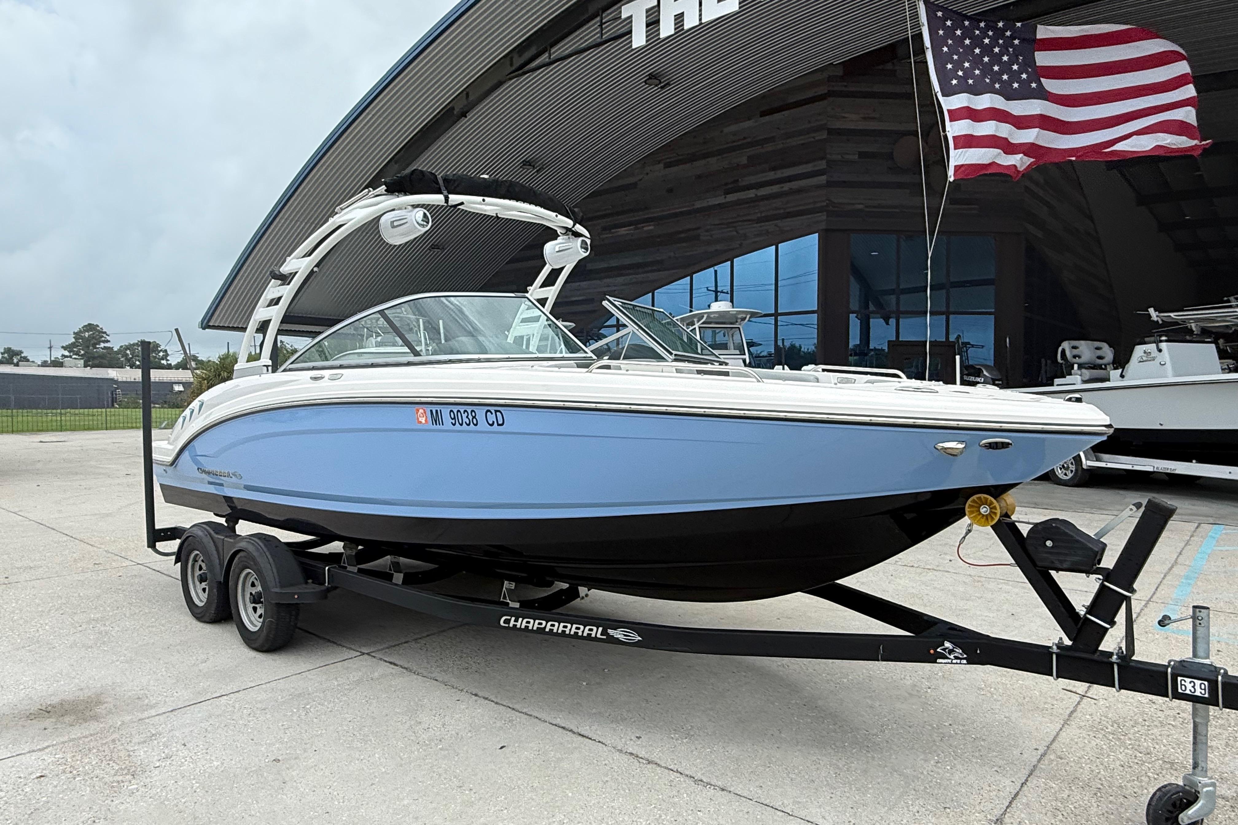 2023 Chaparral 230 SSi boat on trailer, displayed outdoors with American flag.